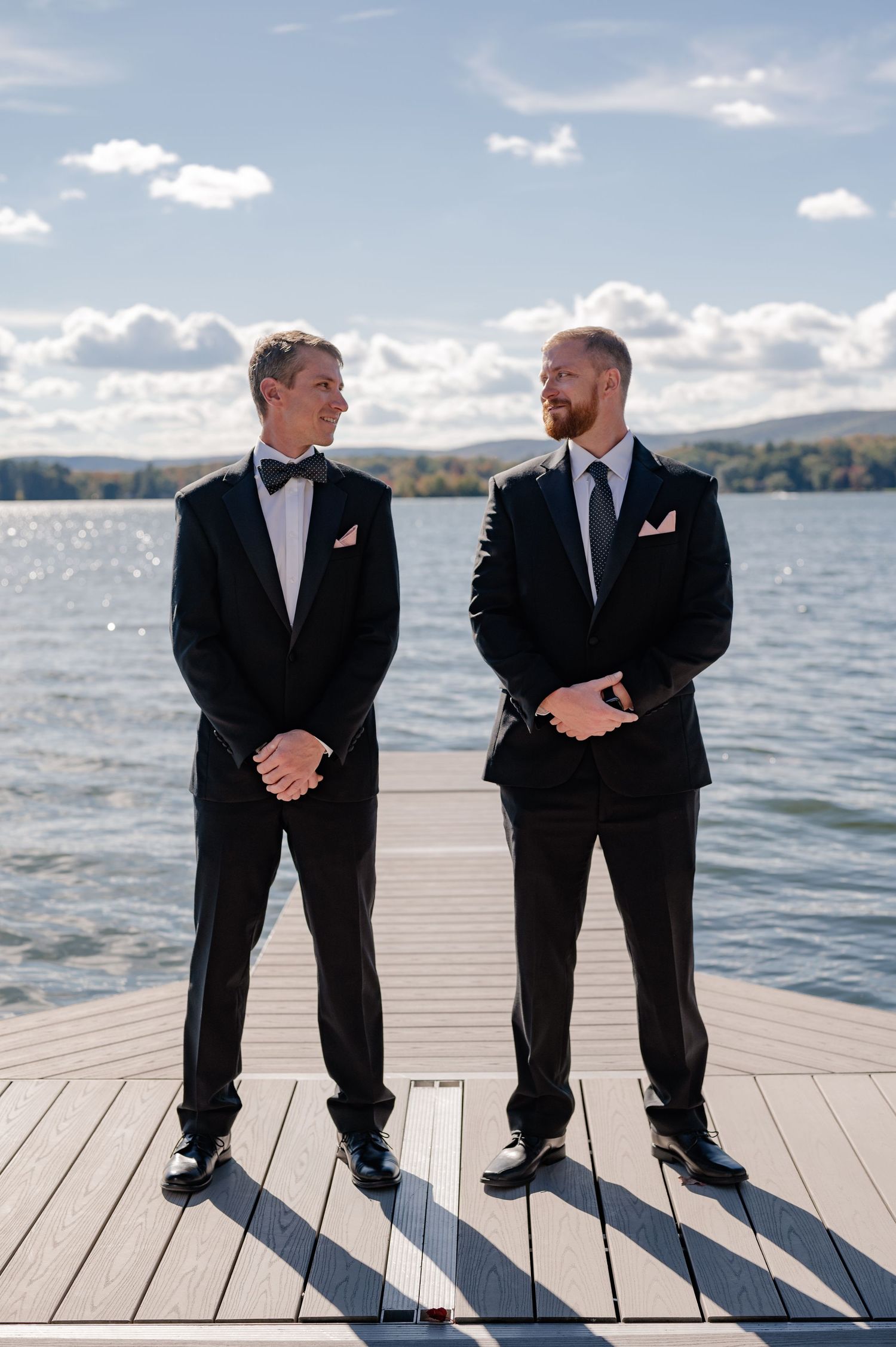 Documentary style candid of a groom & his best man during family photos overlooking mountains and lake in the Berkshires Massachusetts