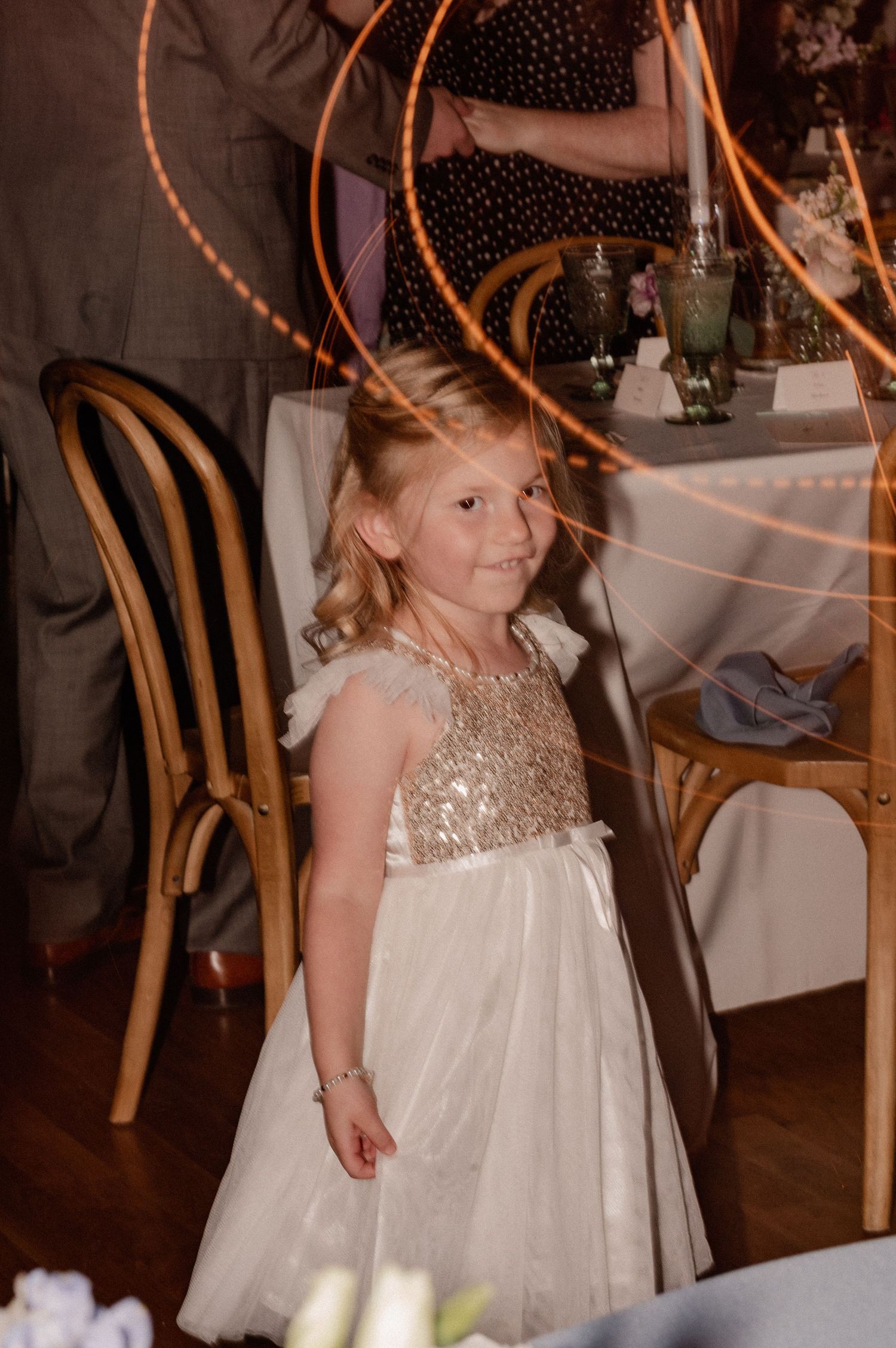 Young wedding guest in sparkly white dress enjoying wedding reception.