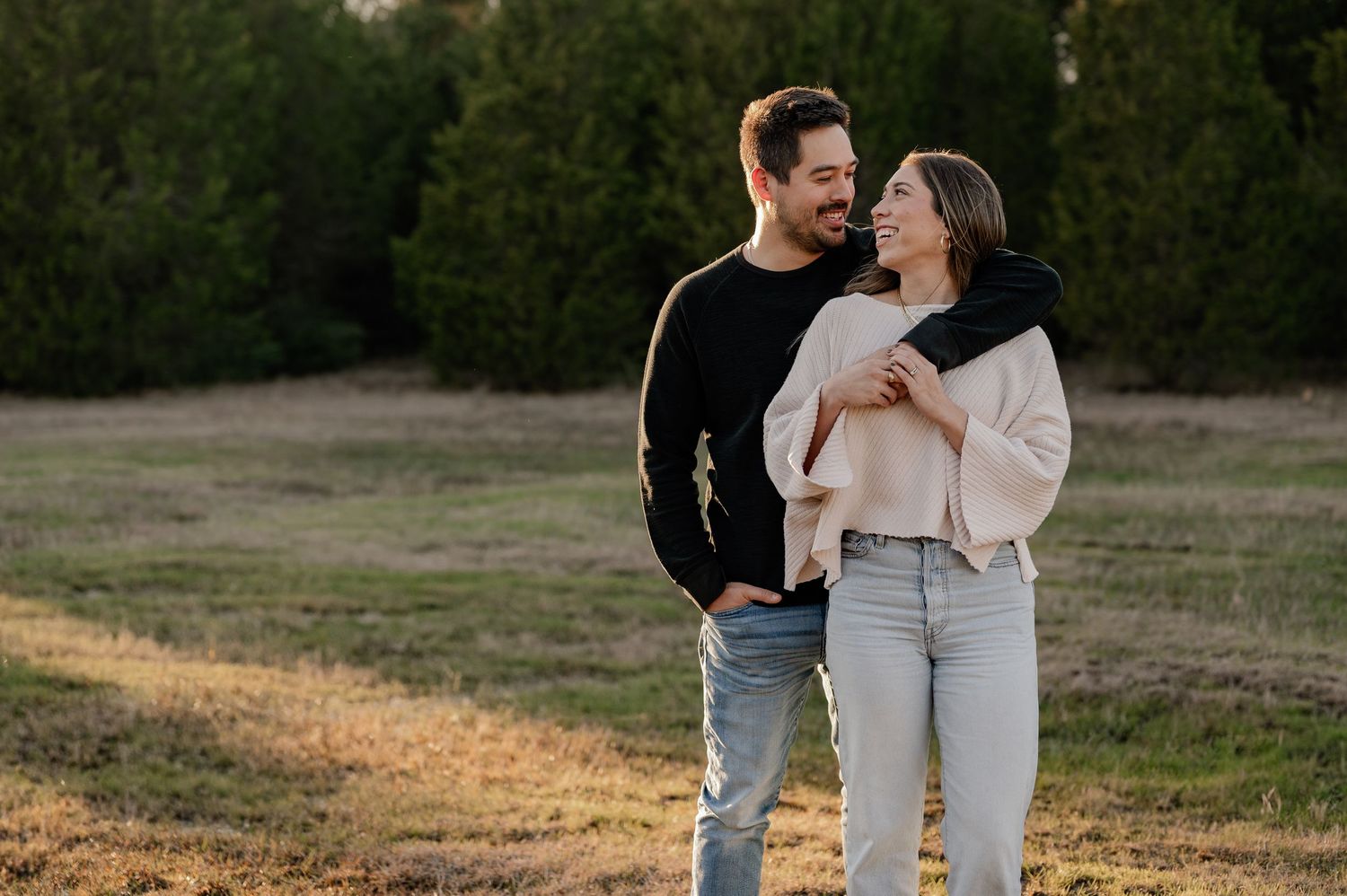 Joyful candid of couple hugging at a couple's photo session in a large tree lined field in Sunnyvale, Texas
