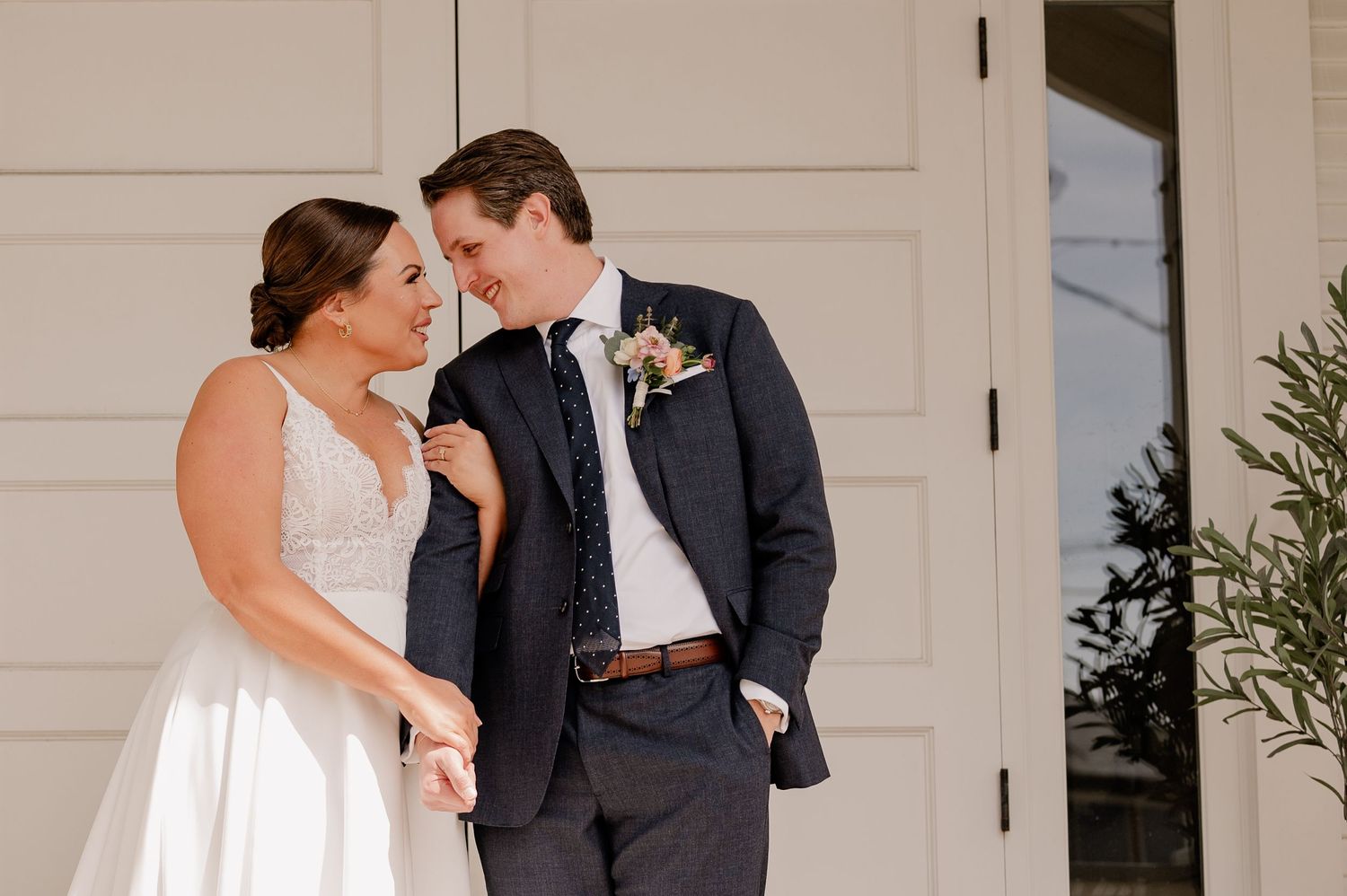 Intimate first look moments captured between bride and groom in front of white doors of historic Bishop Arts wedding venue