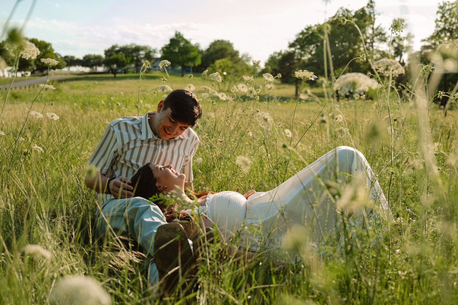 Candid photo of engaged couple during summer engagement session in tall grass in East Dallas, Texas