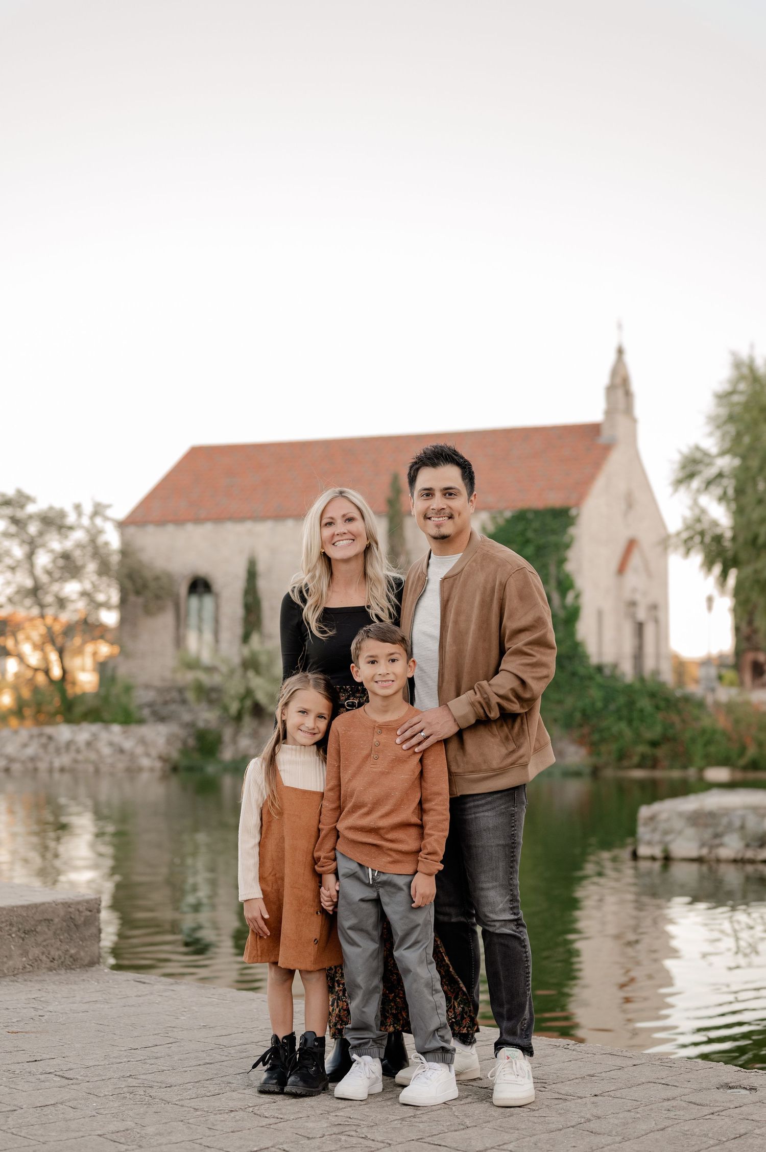 Family of 4 posing in front the Croatian inspired Adriatica chapel for a Fall family photo session in McKinney, Texas