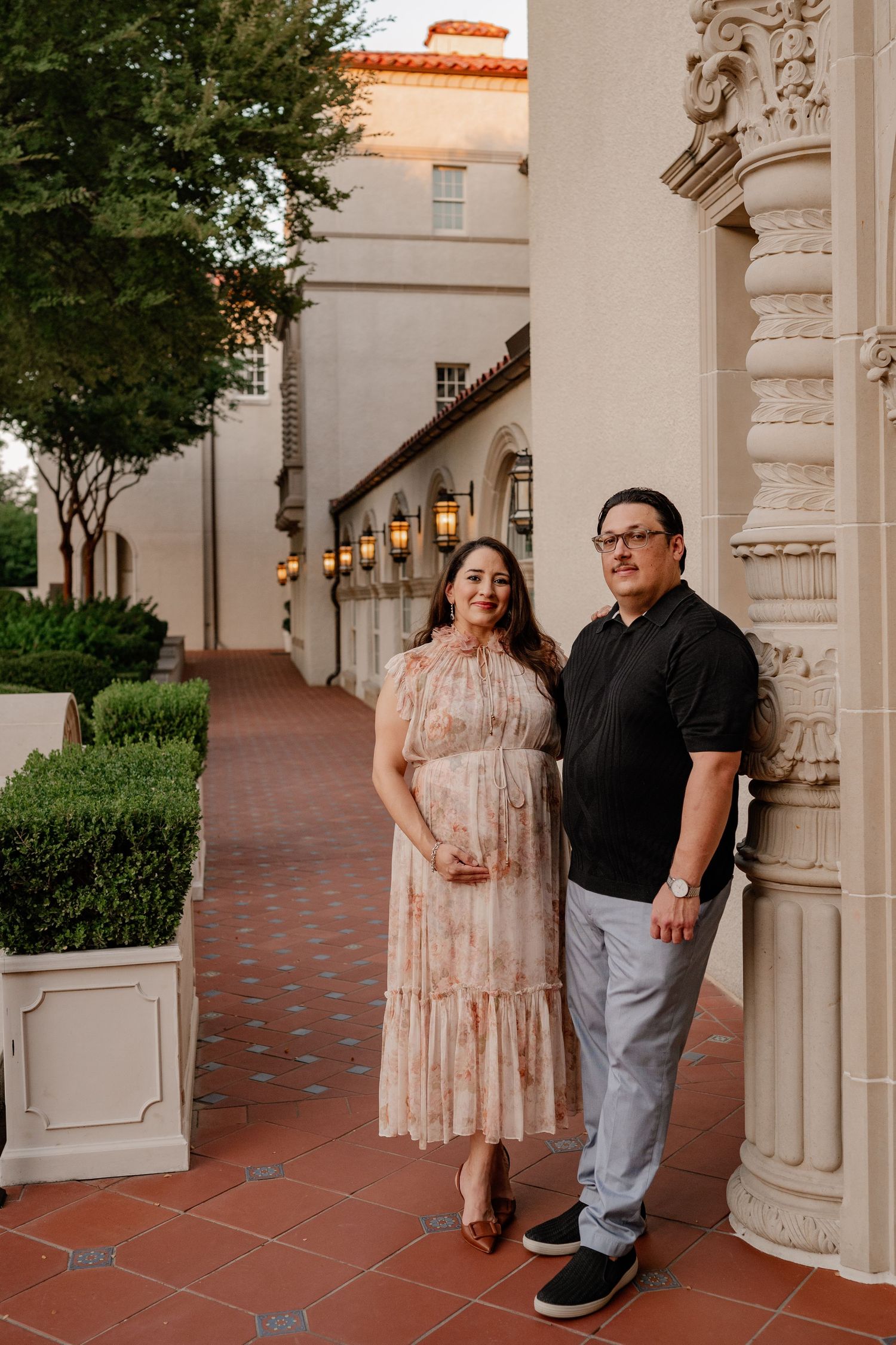 Expecting couple posed outside of an ornate building in Highland Park, Texas for their Spring maternity photo session