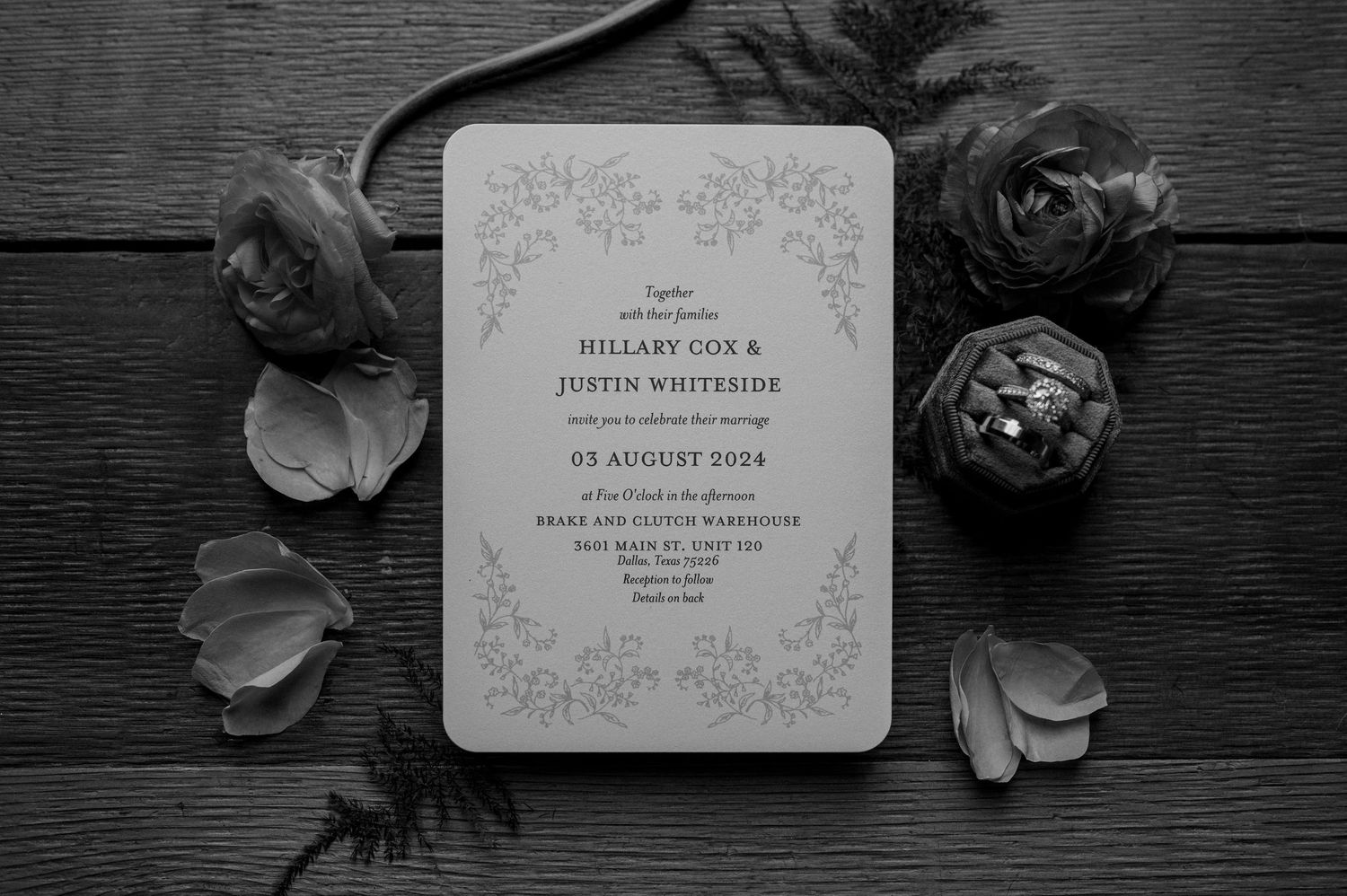 Black and white image of a wedding save the date with wedding florals and a wedding ring box