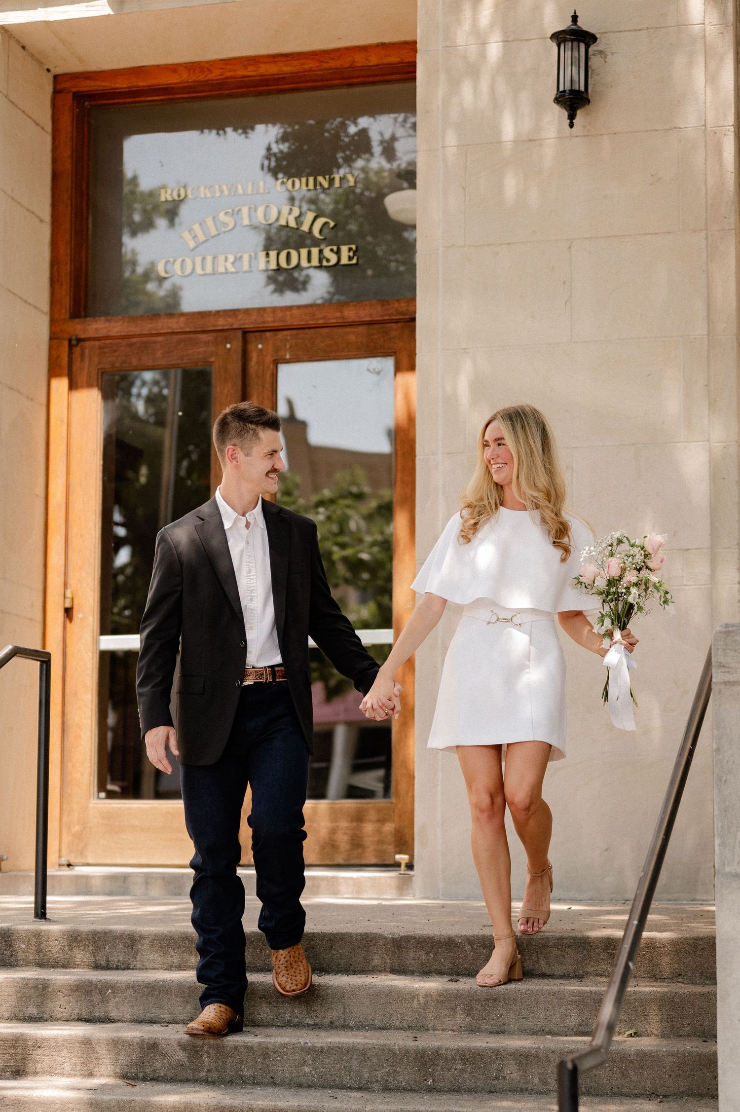 Married couple walking down a staircase outside of the downtown Rockwall courthouse during elopement wedding photo session