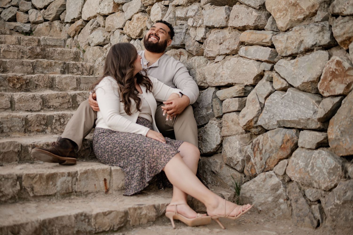 Couple candidly sitting & laughing on steps at  the Croatian inspired Adriatica Village for a Fall couples photo session in McKinney, Texas