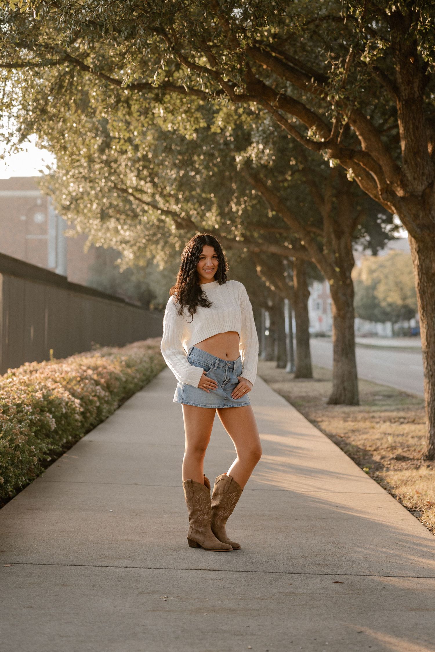 Senior girl posing in warm leaking sunshine down a boulevard on the SMU Campus for a winter Senior photo session