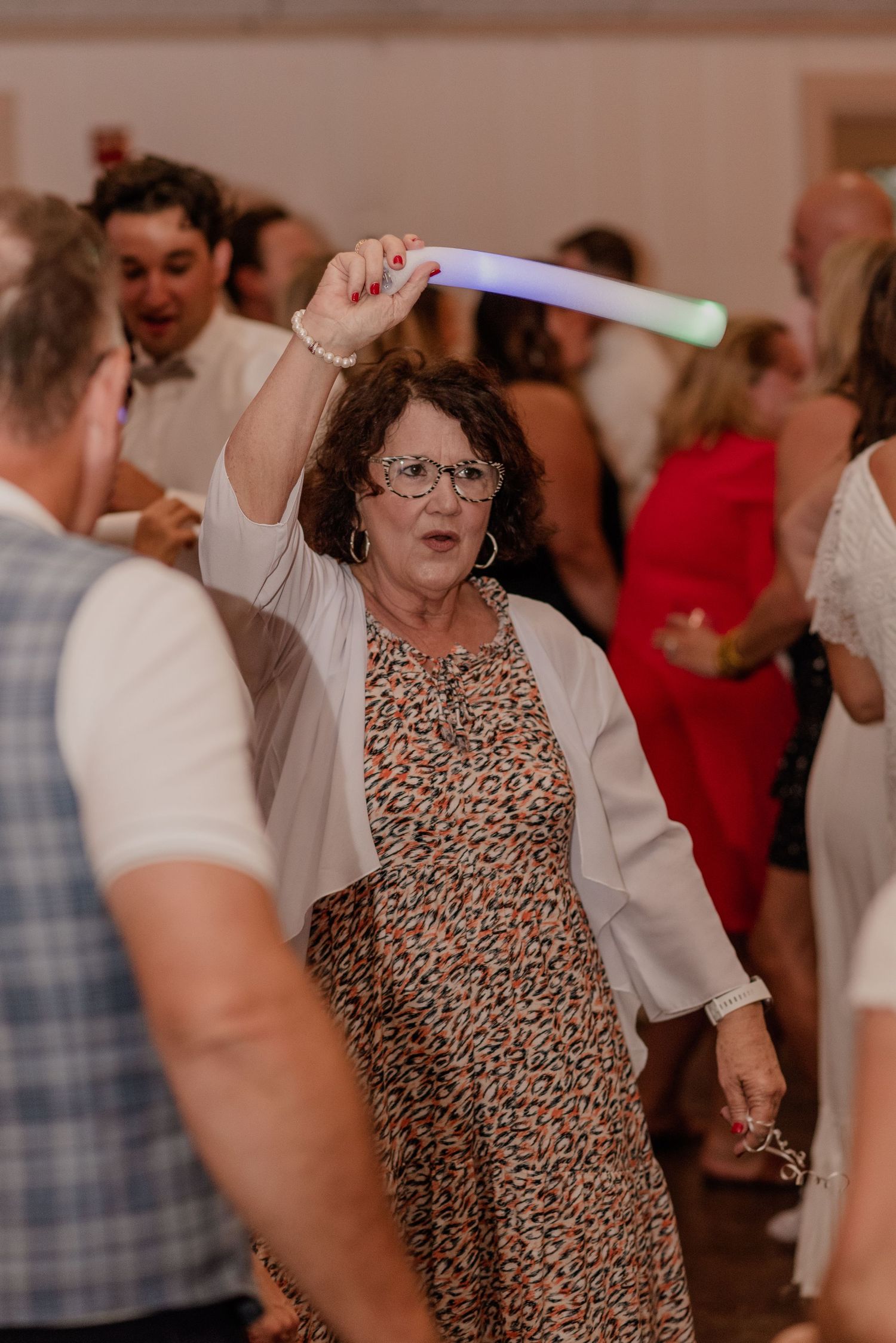 Guest with light-up glow stick dances enthusiastically at wedding reception.