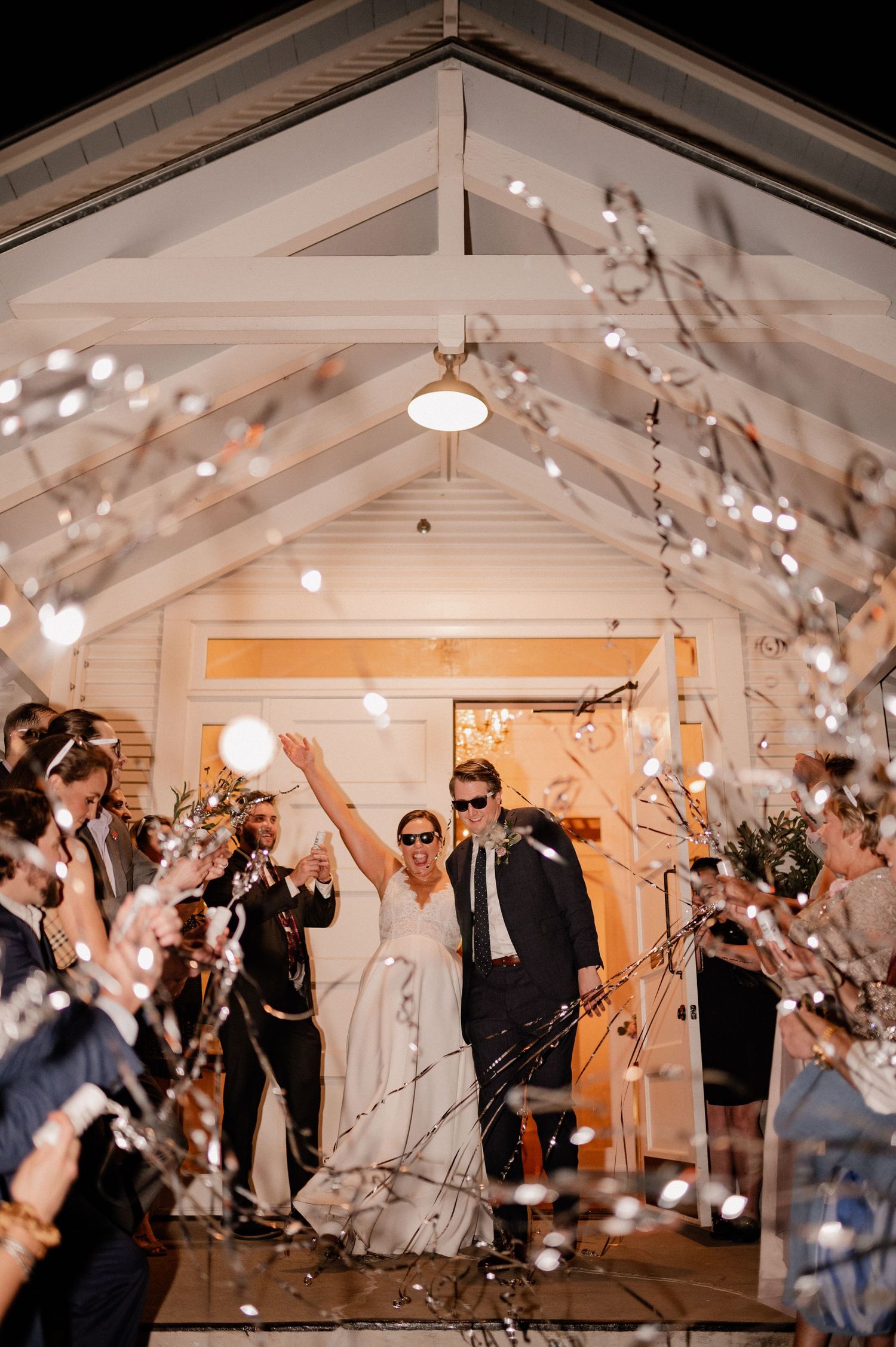 Joyful exit from wedding reception with guests popping streamers outside of Bishop Arts venue in Dallas, Texas