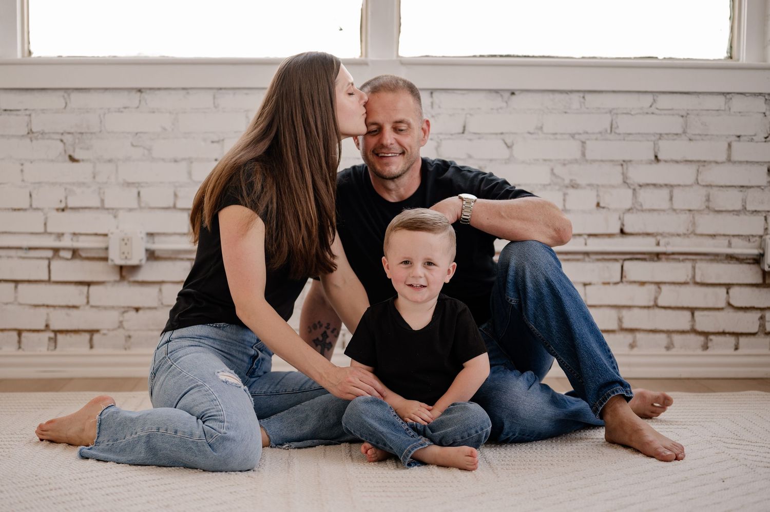Candid lifestyle photo showing affectionate embraces at a family photo session in a bright indoor studio in Dallas, Texas