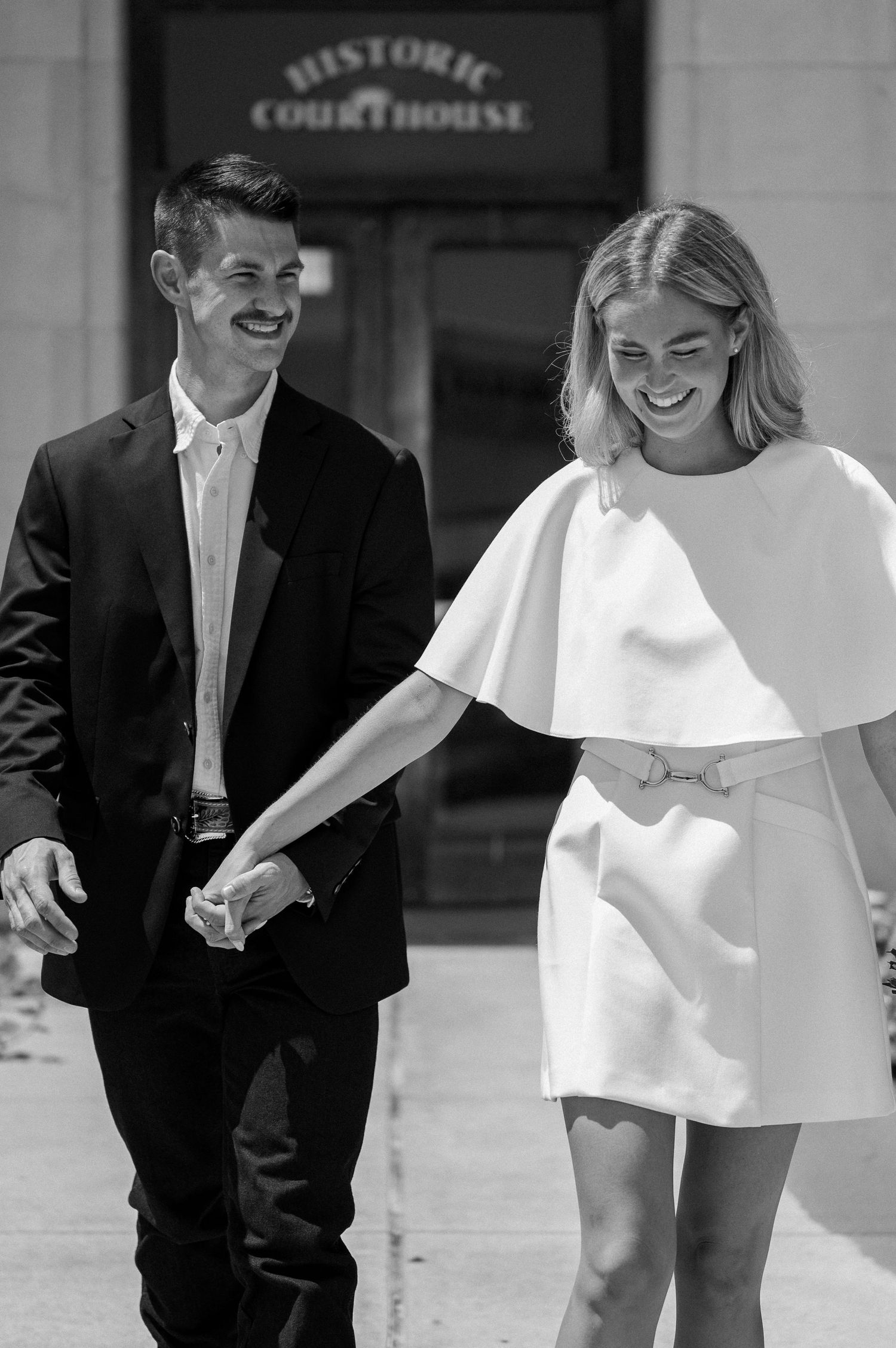 Black and white playful married couple outside of downtown Rockwall courthouse during elopement wedding photo session