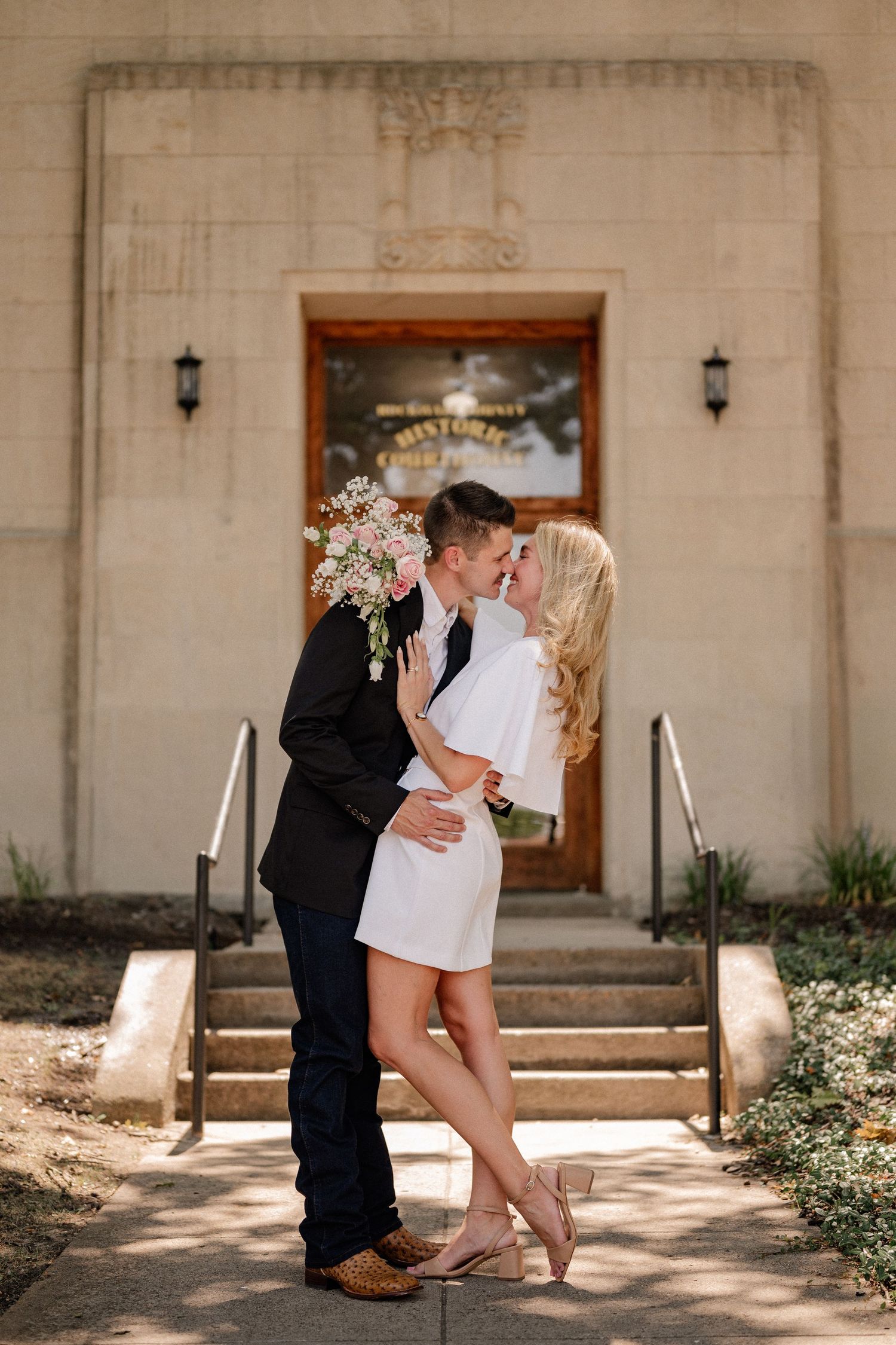Married couple romantically kissing outside of the downtown Rockwall courthouse during elopement wedding photo session