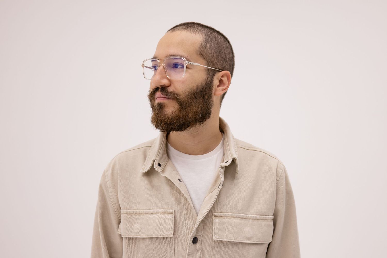 A serious headshot portrait of a male musician in front of a white studio wall