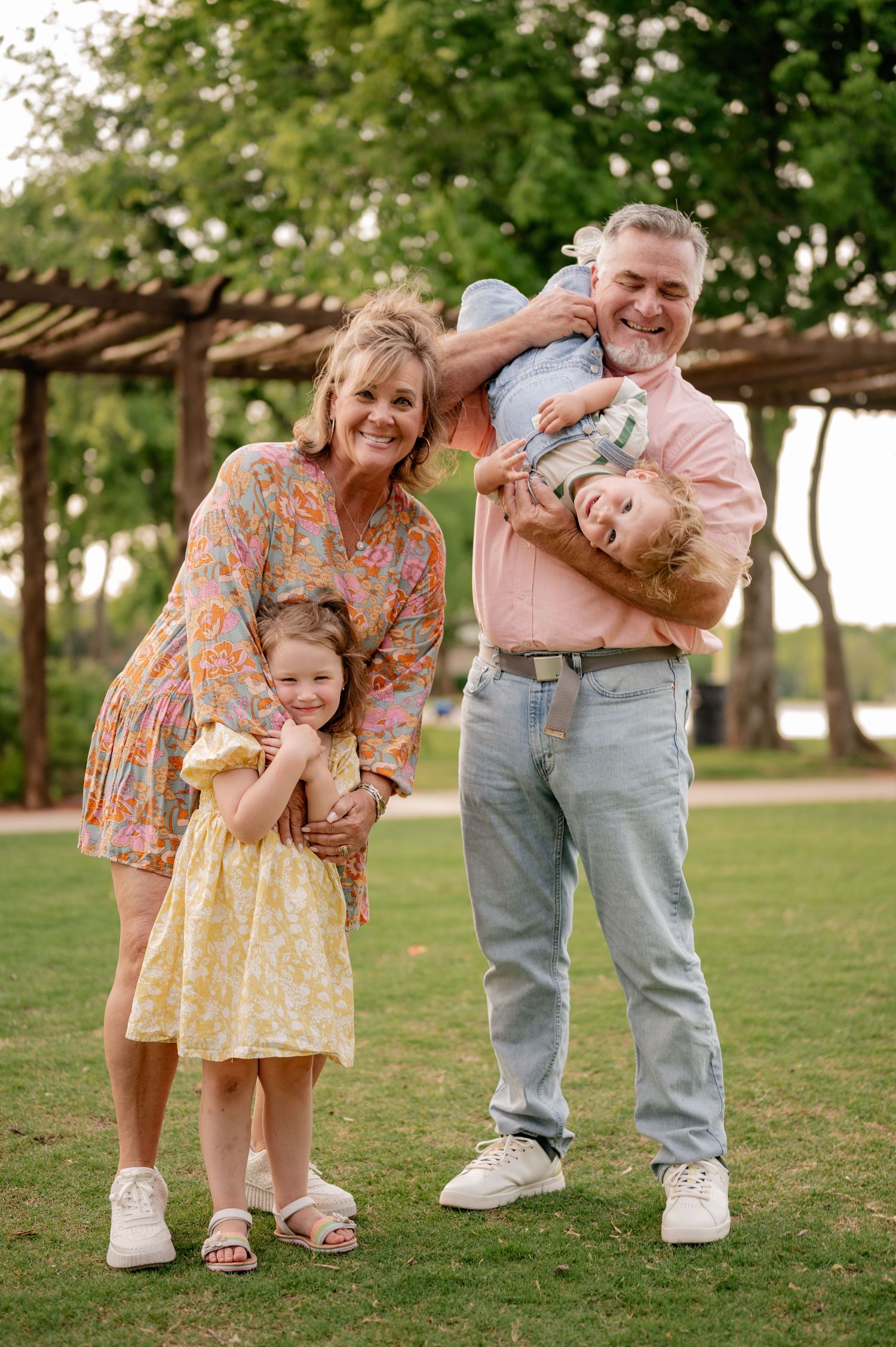 Grandparents playing and posing with grandkids for an outdoor summer family photo session in Rockwall, Texas
