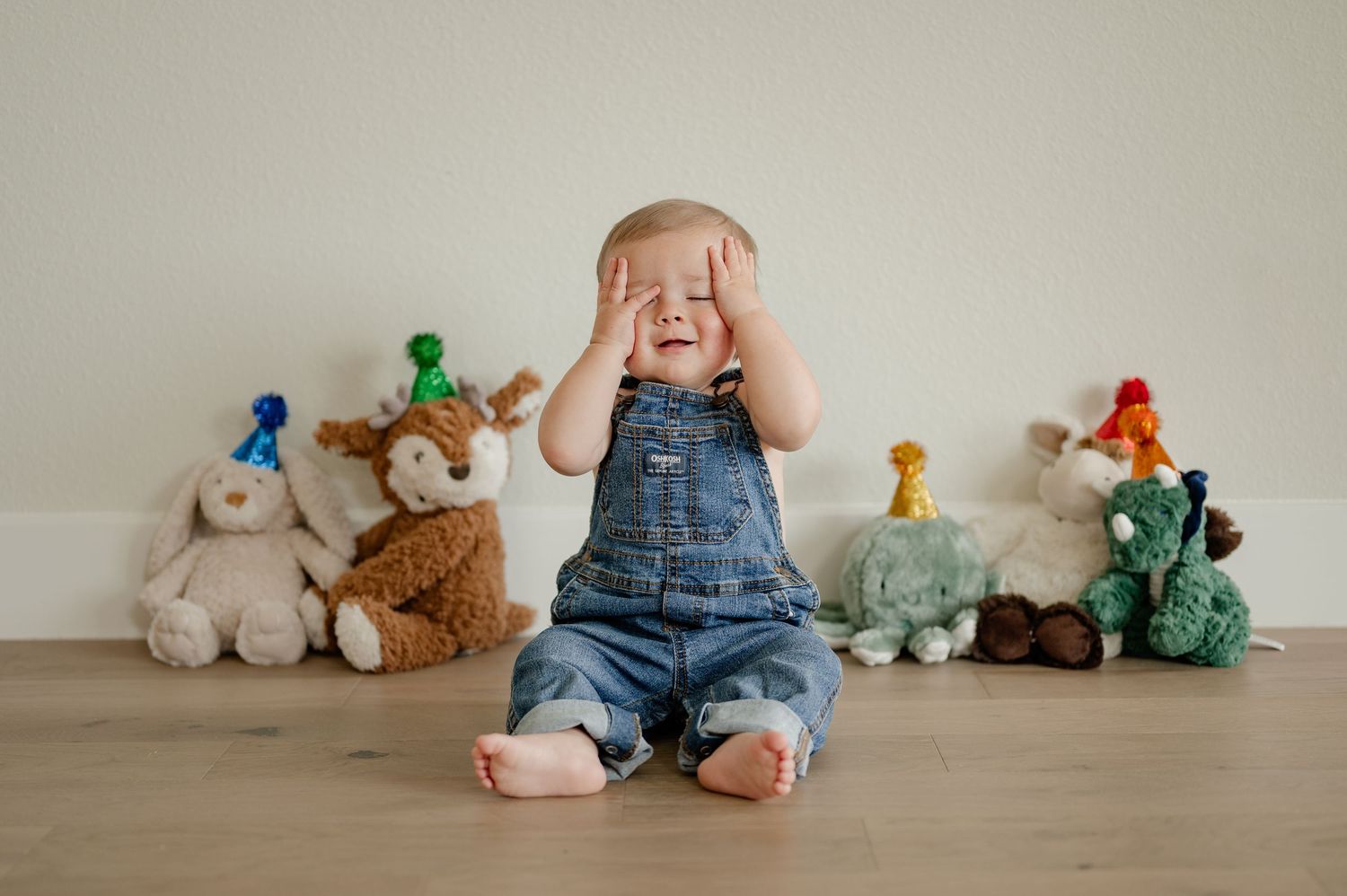 Memento session of a one year old sitting on the floor with his stuffed animals in party hats for an at-home session in Rockwall, TX