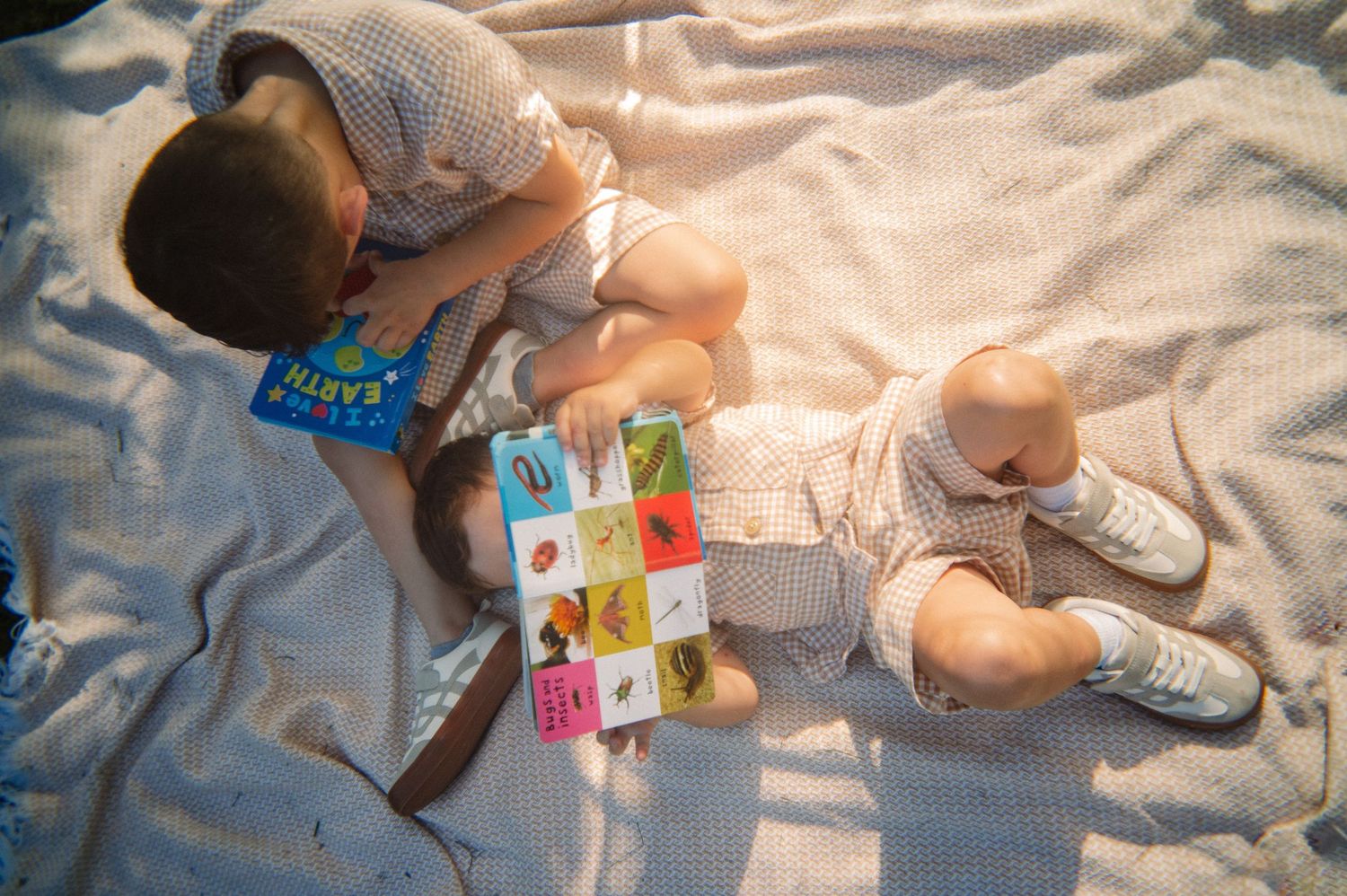 Two boys sitting and laying on a blanket reading books at golden hour during a spring at-home family session in Dallas, Texas