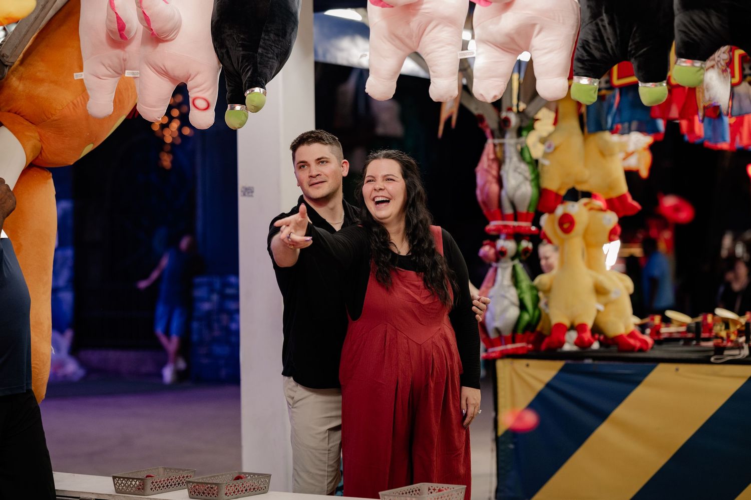 A married couple plays a ring toss game at the State Fair of Texas during a maternity session announcing their pregnancy