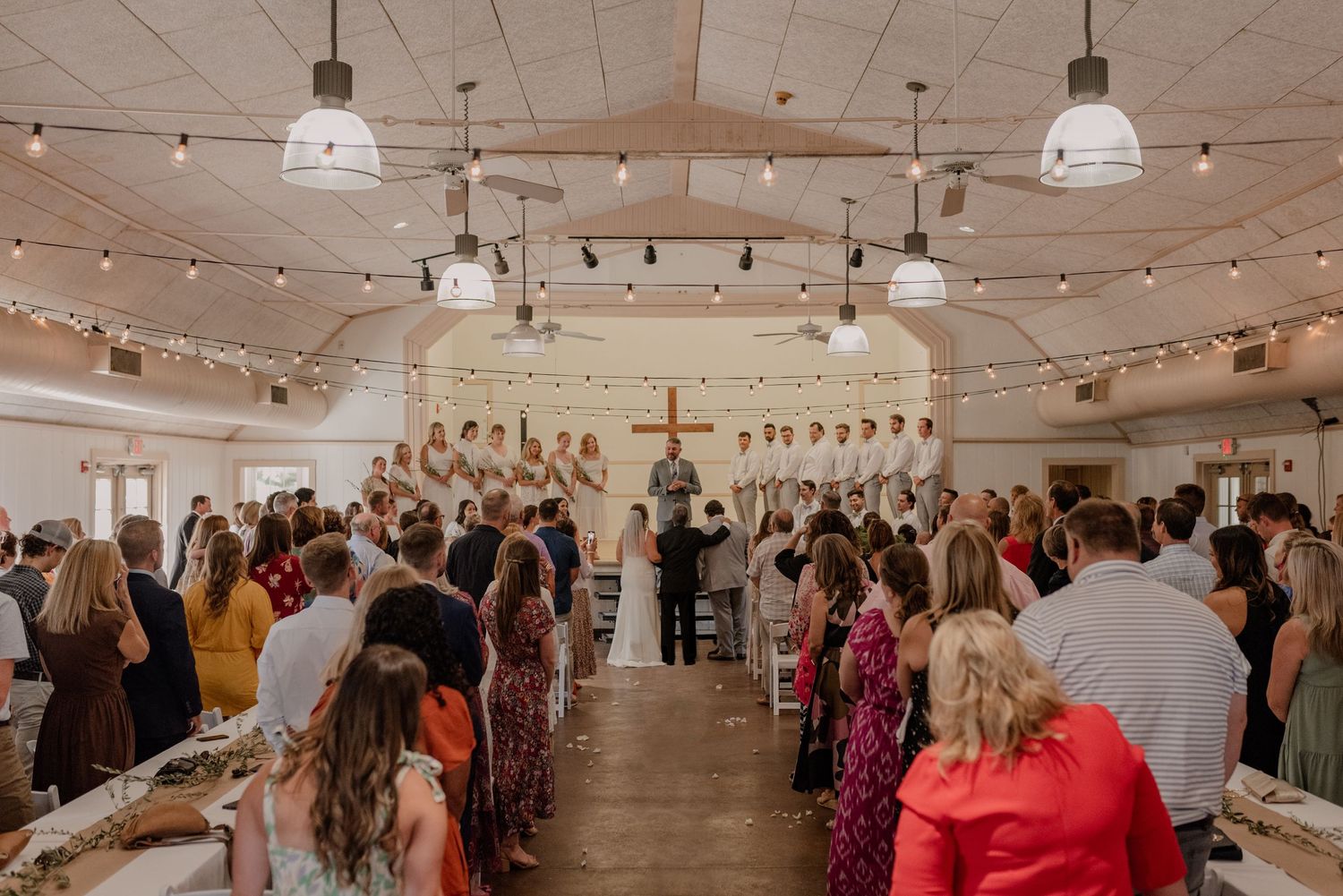 An indoor wedding reception venue decorated with string lights and white decor.