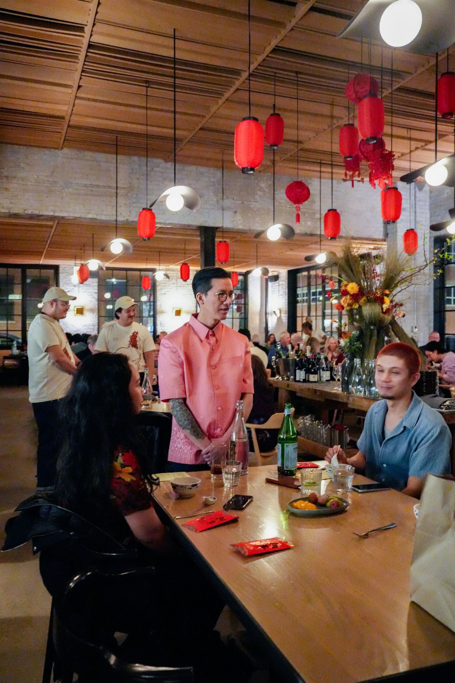 Restaurant interior decorated with red Chinese lanterns features diners seated at wooden tables in a modern space.