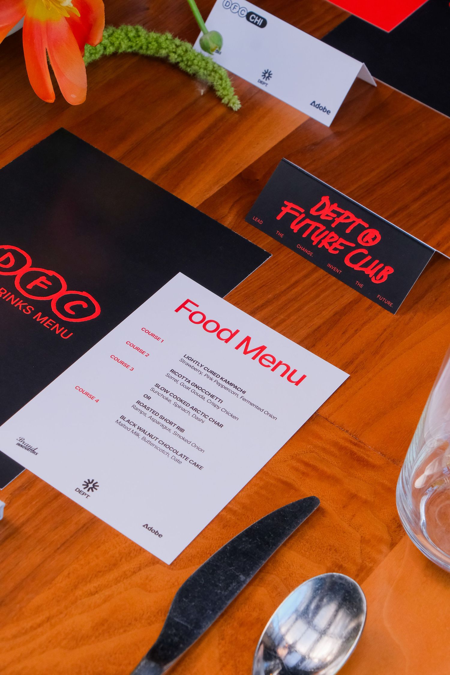 A restaurant table setting with a Food Menu and Dept of Future Club cards on a wooden surface.