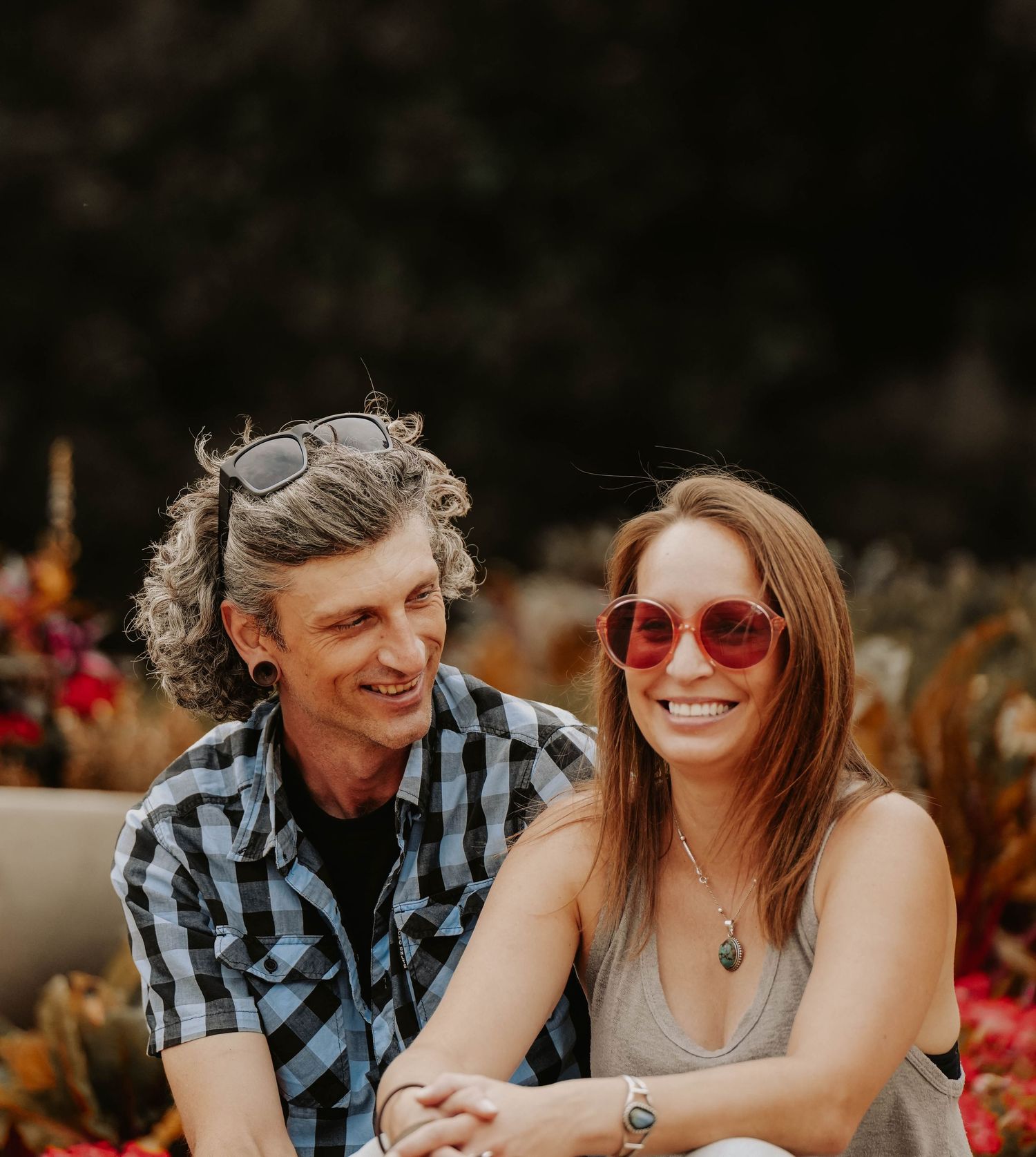 Couple sharing joyful moments together on wooden bench in autumn setting.