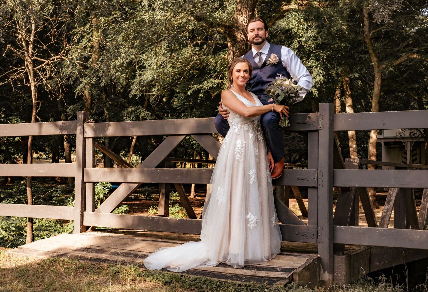 Rustic outdoor wedding venue with wooden fencing and natural greenery backdrop.