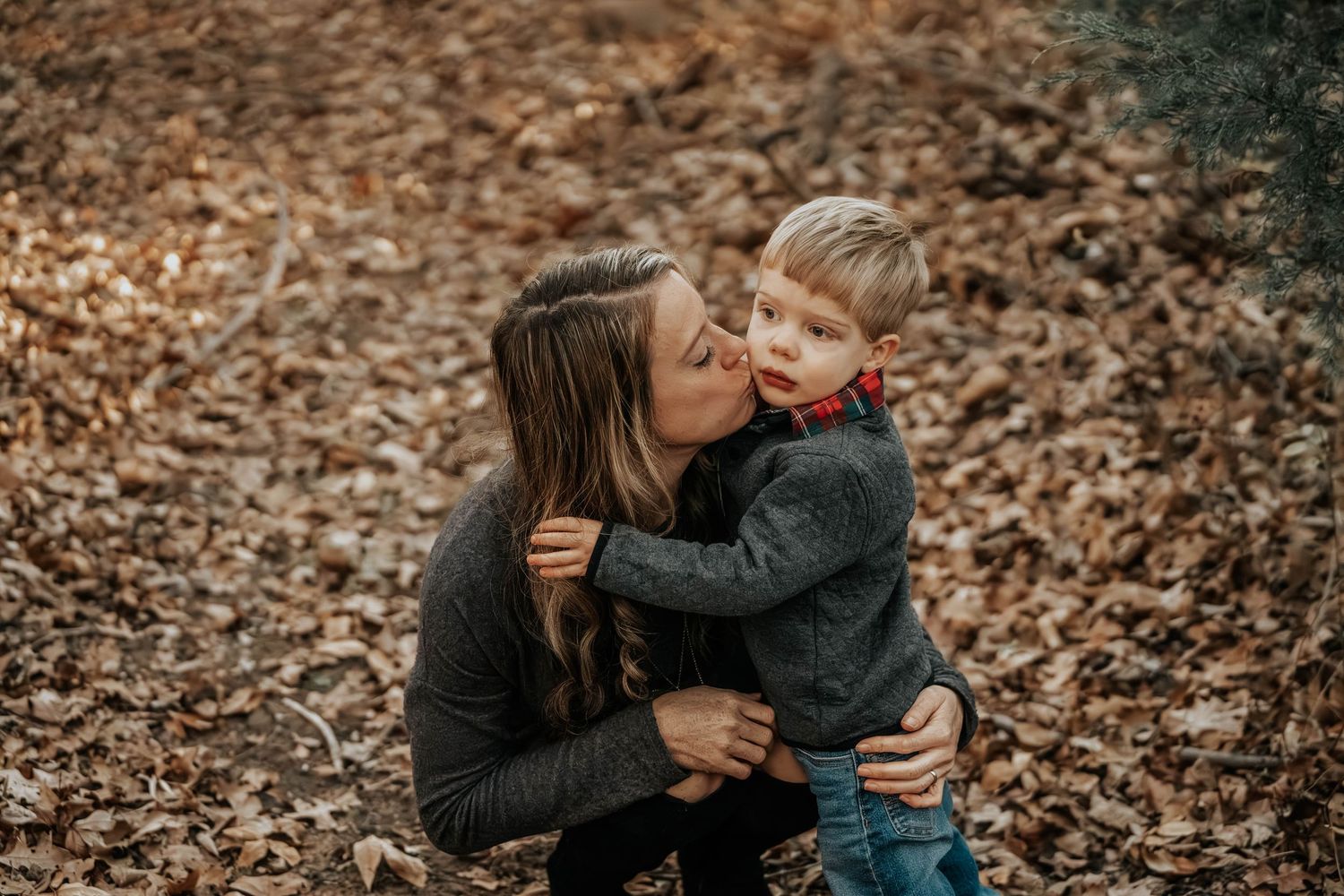A tender moment captured between parent and child among fallen autumn leaves.