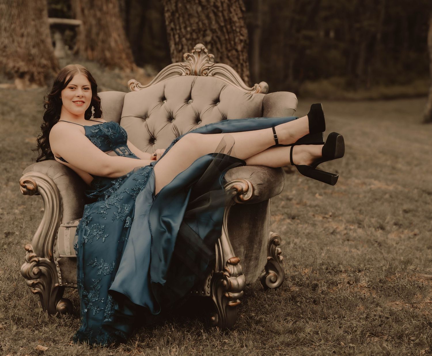 Vintage styled portrait with person lounging on ornate tufted sofa outdoors.