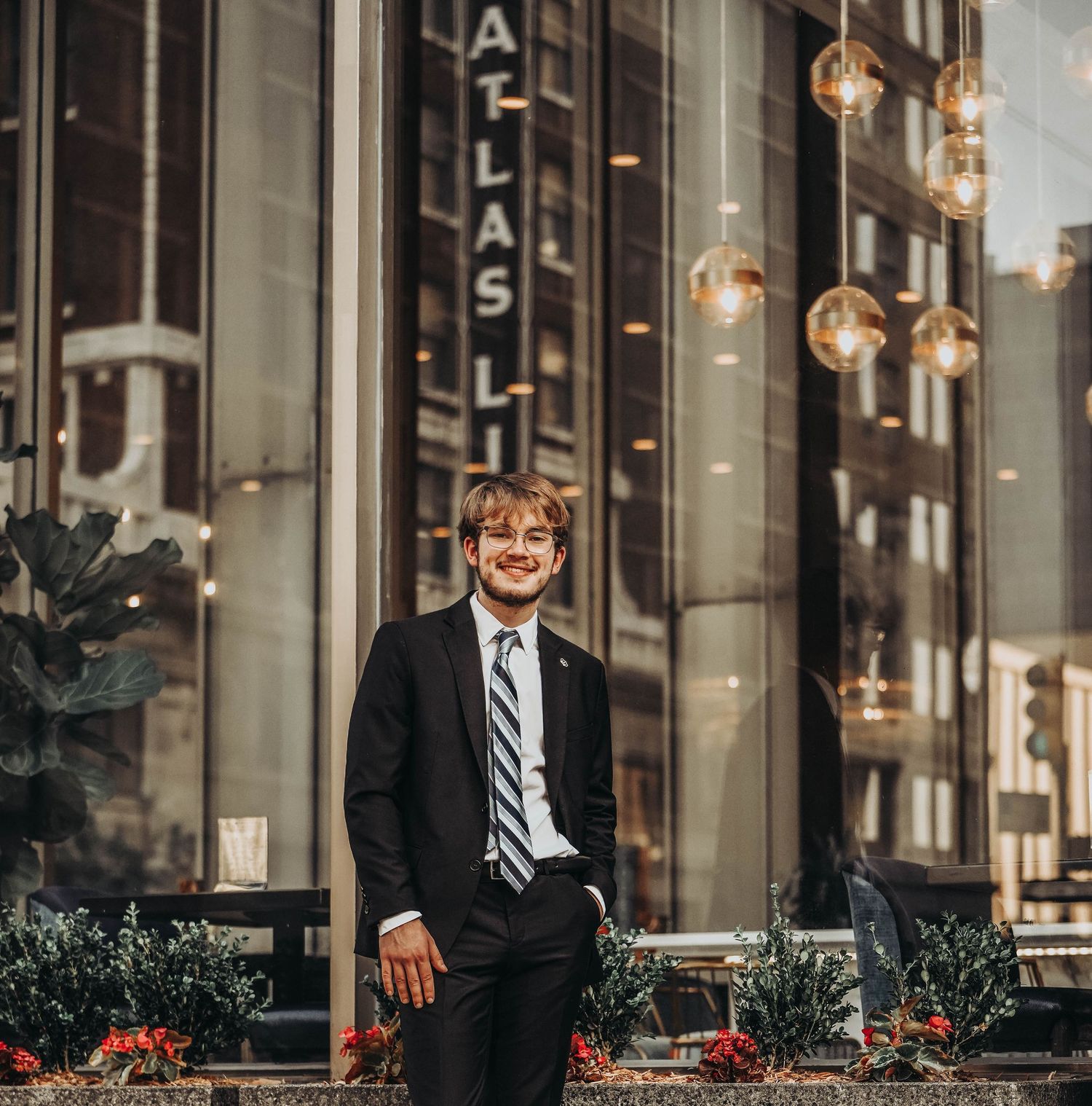 Urban storefront portrait with decorative flowers and professional attire.