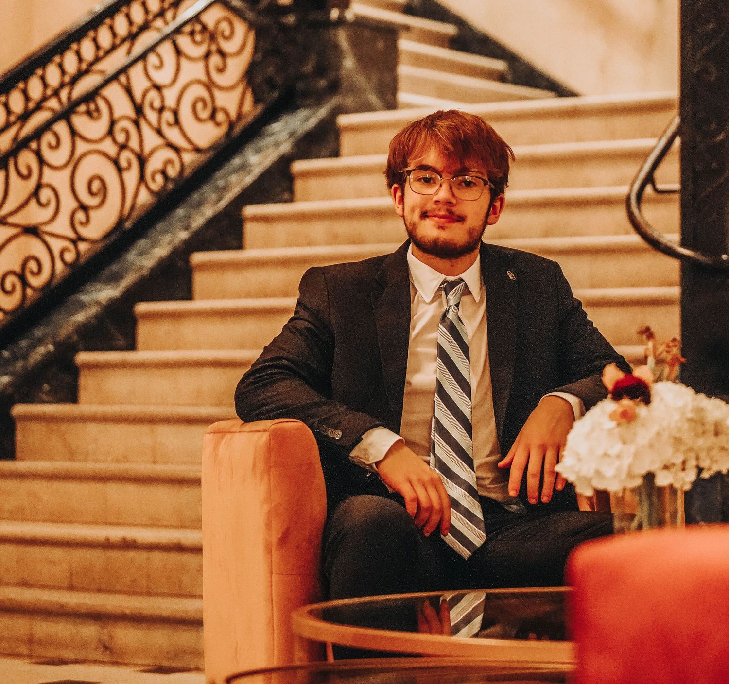 Elegant formal portrait on ornate staircase with warm lighting.