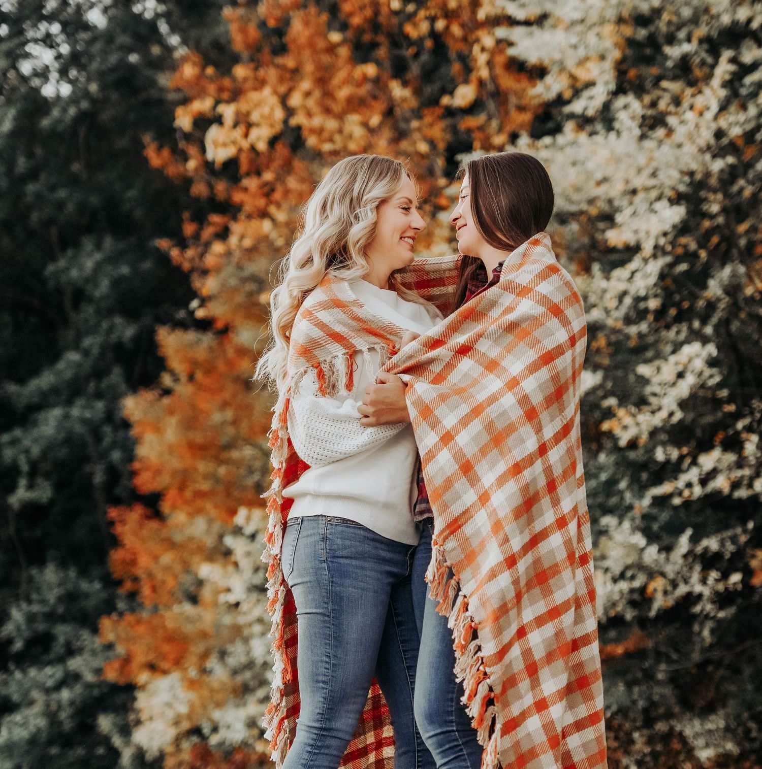 Cozy autumn couples photography with plaid blankets and warm embraces against fall foliage.