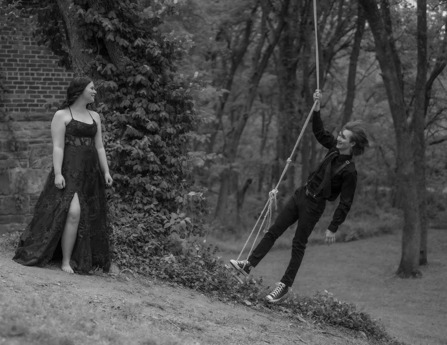 Black and white photo of people playing and running through wooded area.