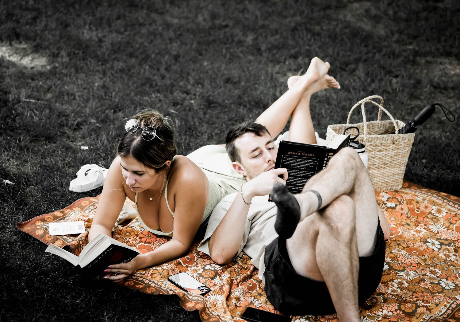 People lying on a blanket reading books together in the park