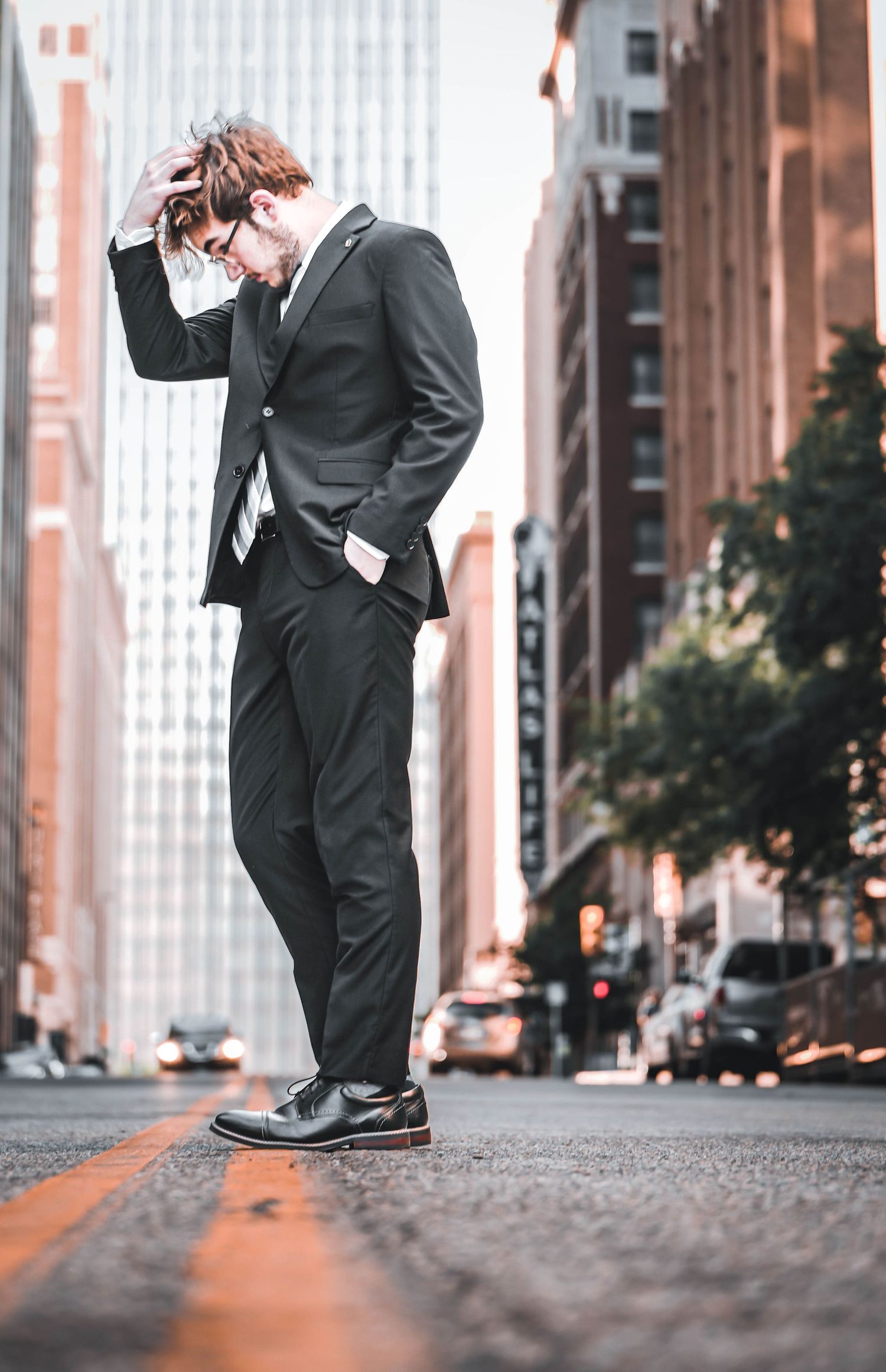 Urban street photography focusing on polished dress shoes and suit pants from low angle.
