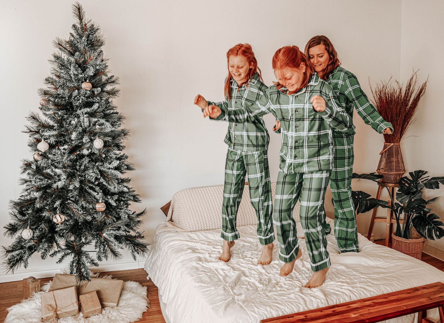 People wearing matching green plaid pajamas near a Christmas tree.