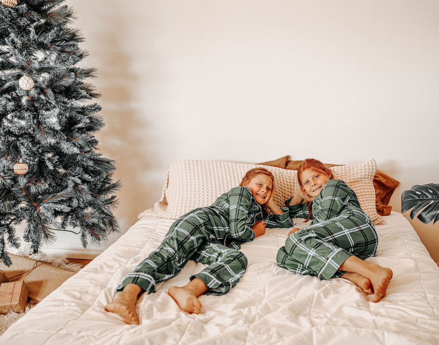 Sequence of people falling onto a white bed in green plaid pajamas.