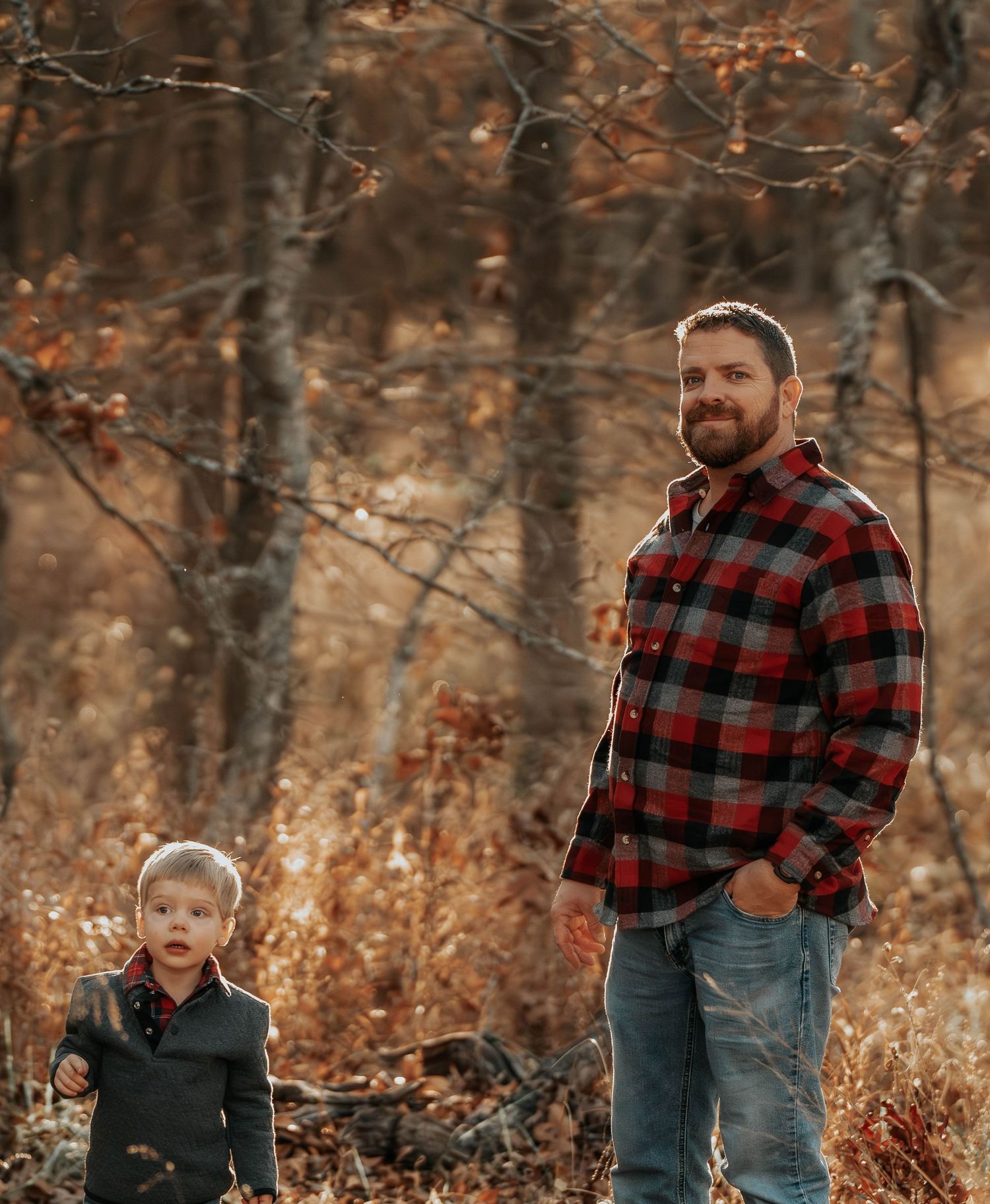 Two people in plaid flannel shirts standing in a fall forest setting.