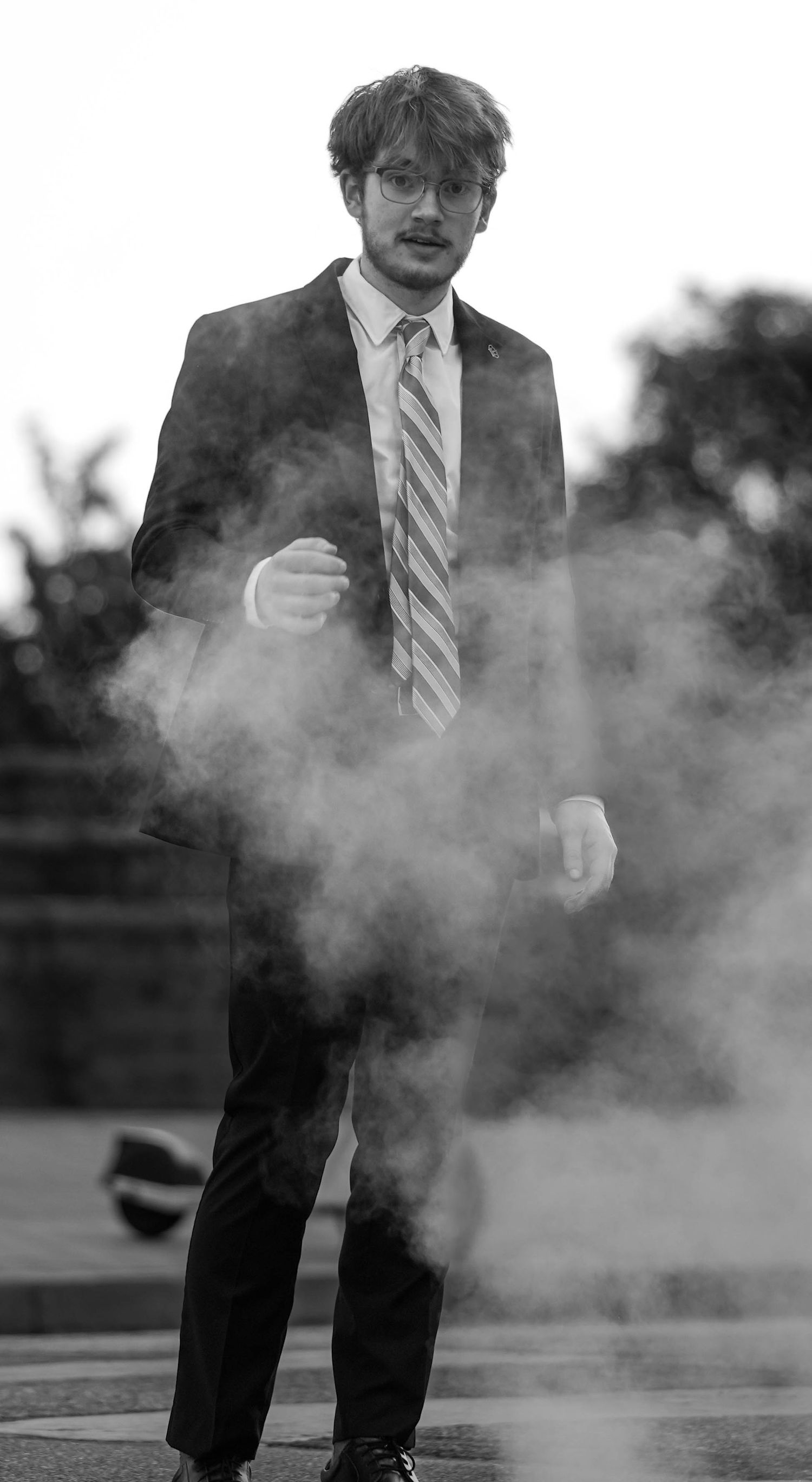 Black and white photo with smoke effects and formal attire in outdoor setting.