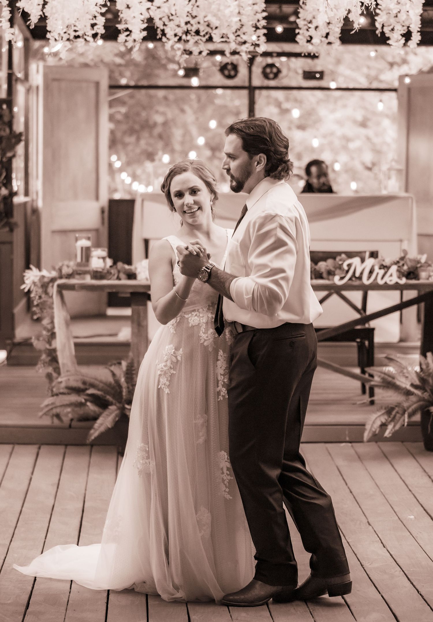 Wedding dance sequence captured on a rustic wooden deck in sepia tones.