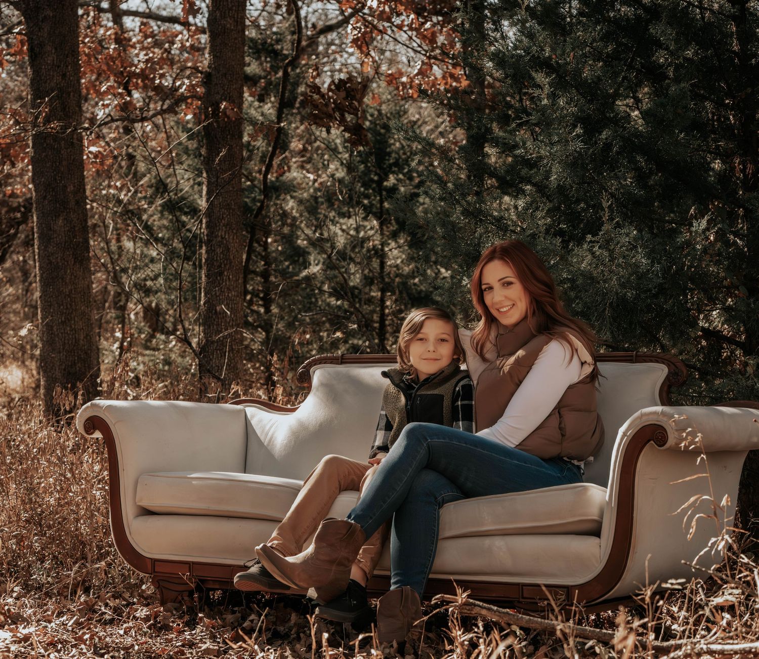 People relaxing on a vintage couch placed outdoors in an autumn forest.
