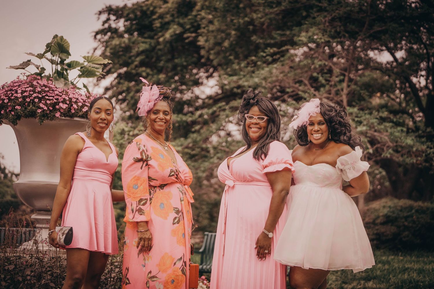 Group photo of wedding party members in matching pink dresses outdoors.
