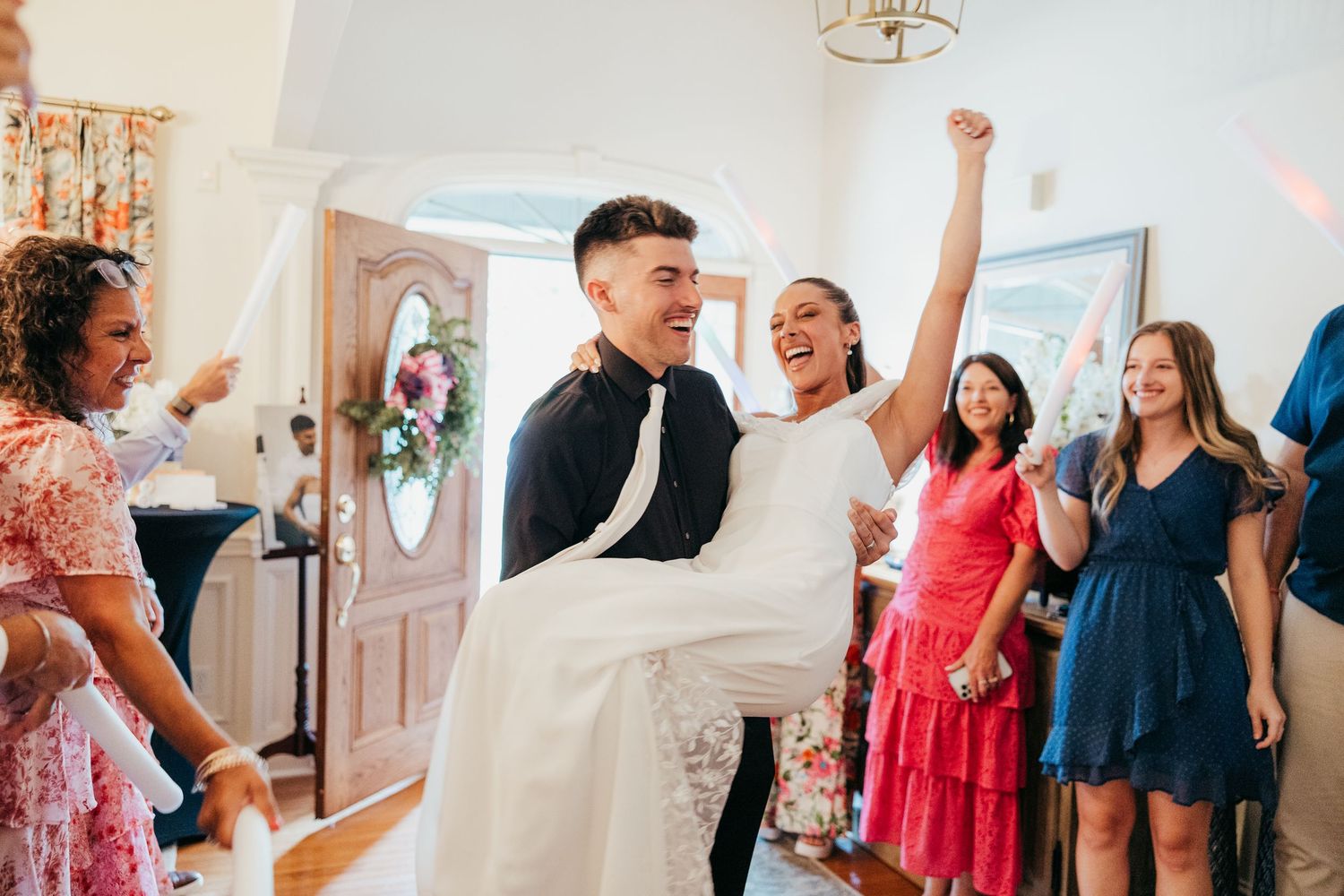 Joyful bride and groom make grand entrance at wedding reception as guests cheer and celebrate.