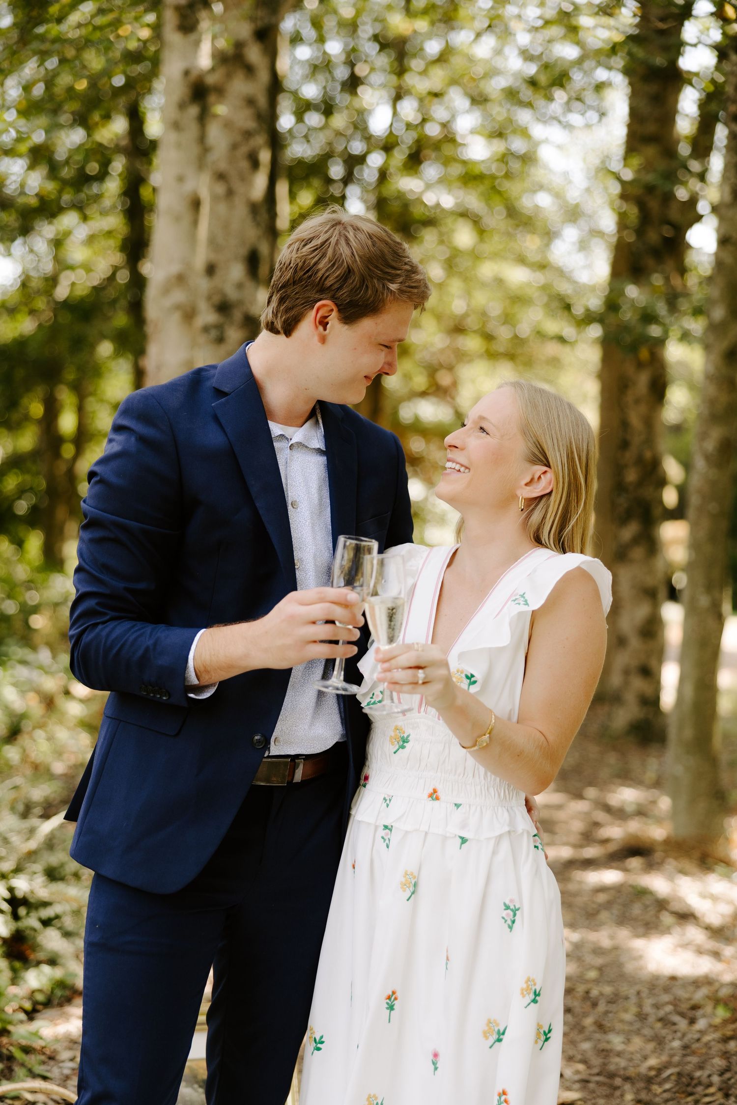Intimate moment shared between a couple toasting with drinks in a forest.