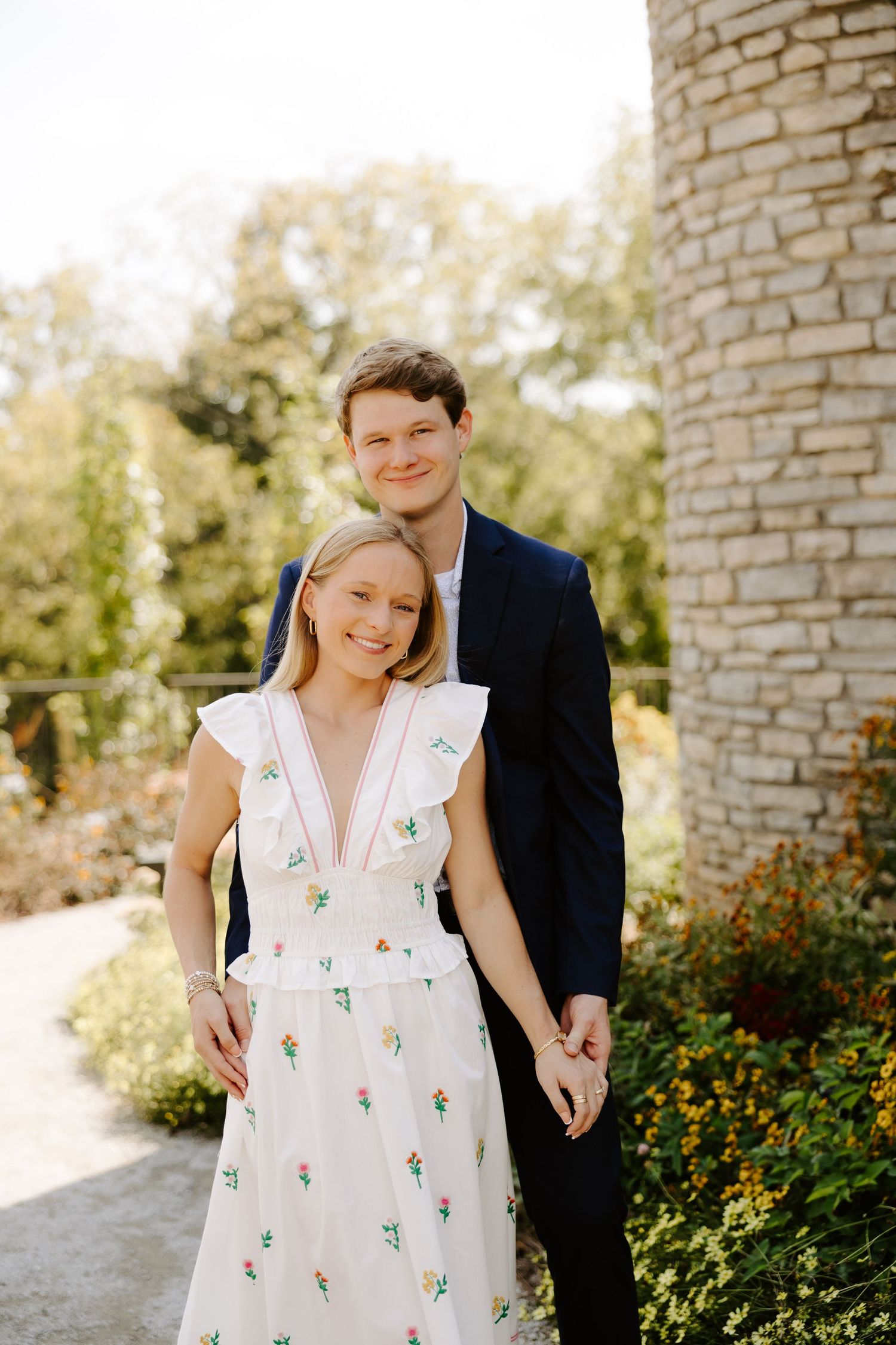 Couple sharing tender moments against a stone wall backdrop outdoors.