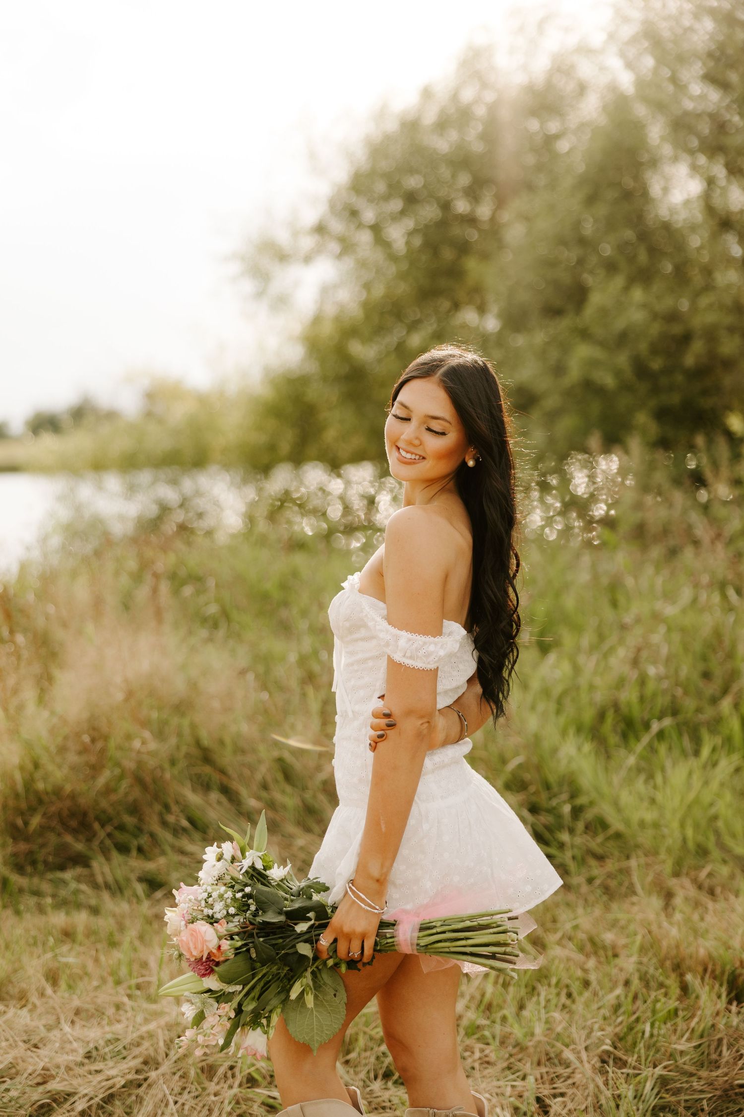 A dreamy summer photoshoot with a floral bouquet in a sunlit field.