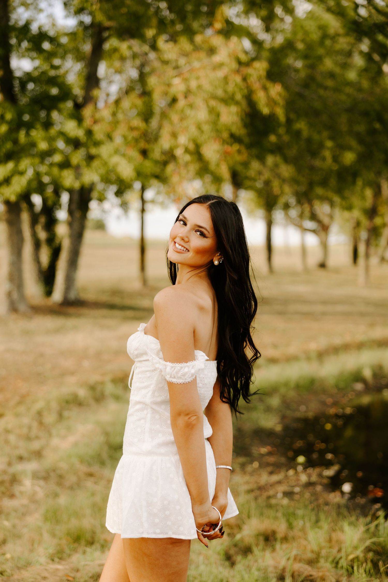 A playful outdoor portrait among autumn trees in a white lace dress.