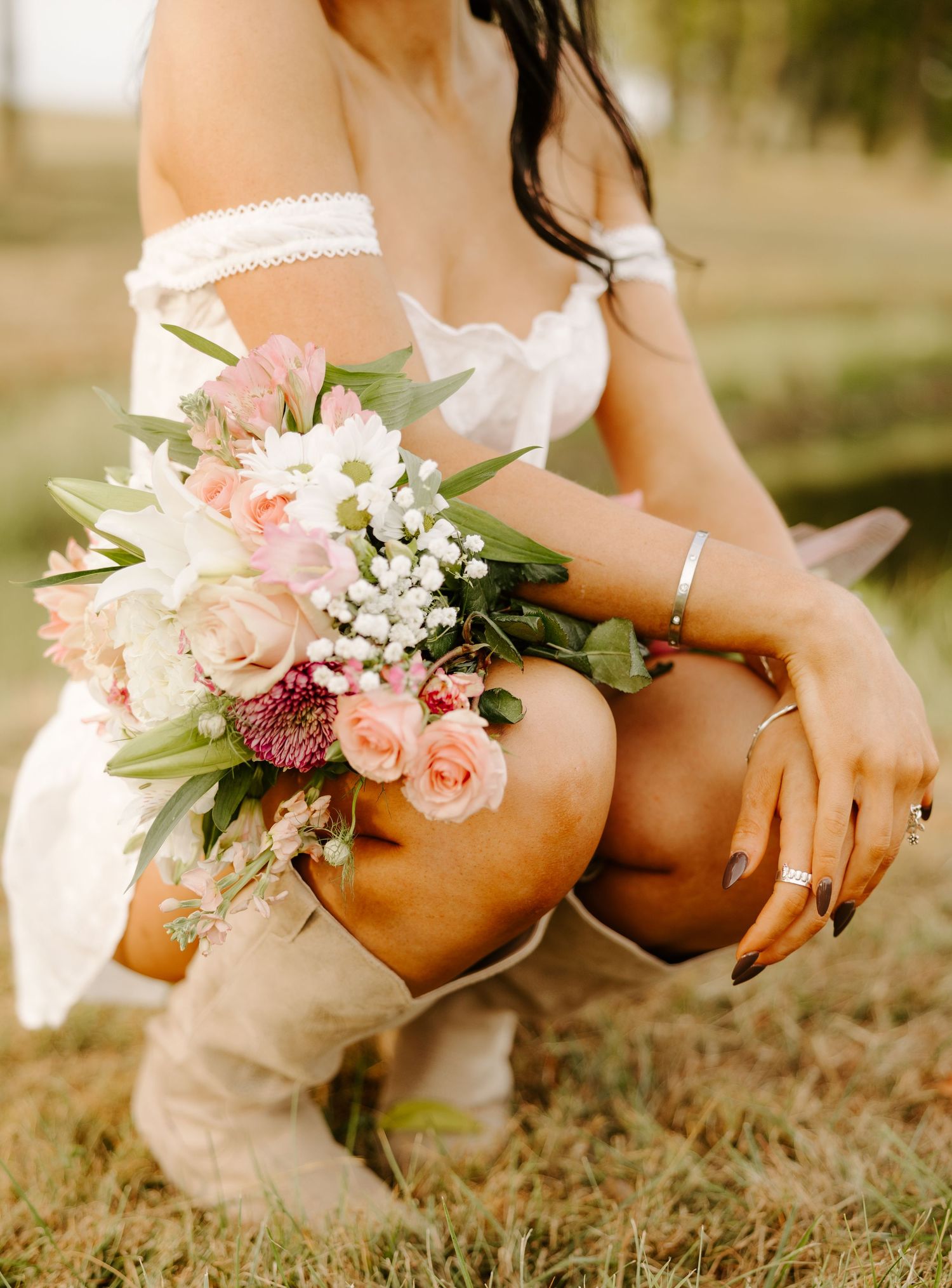 A detailed shot of a delicate pink and white bouquet with boots in a rustic setting.