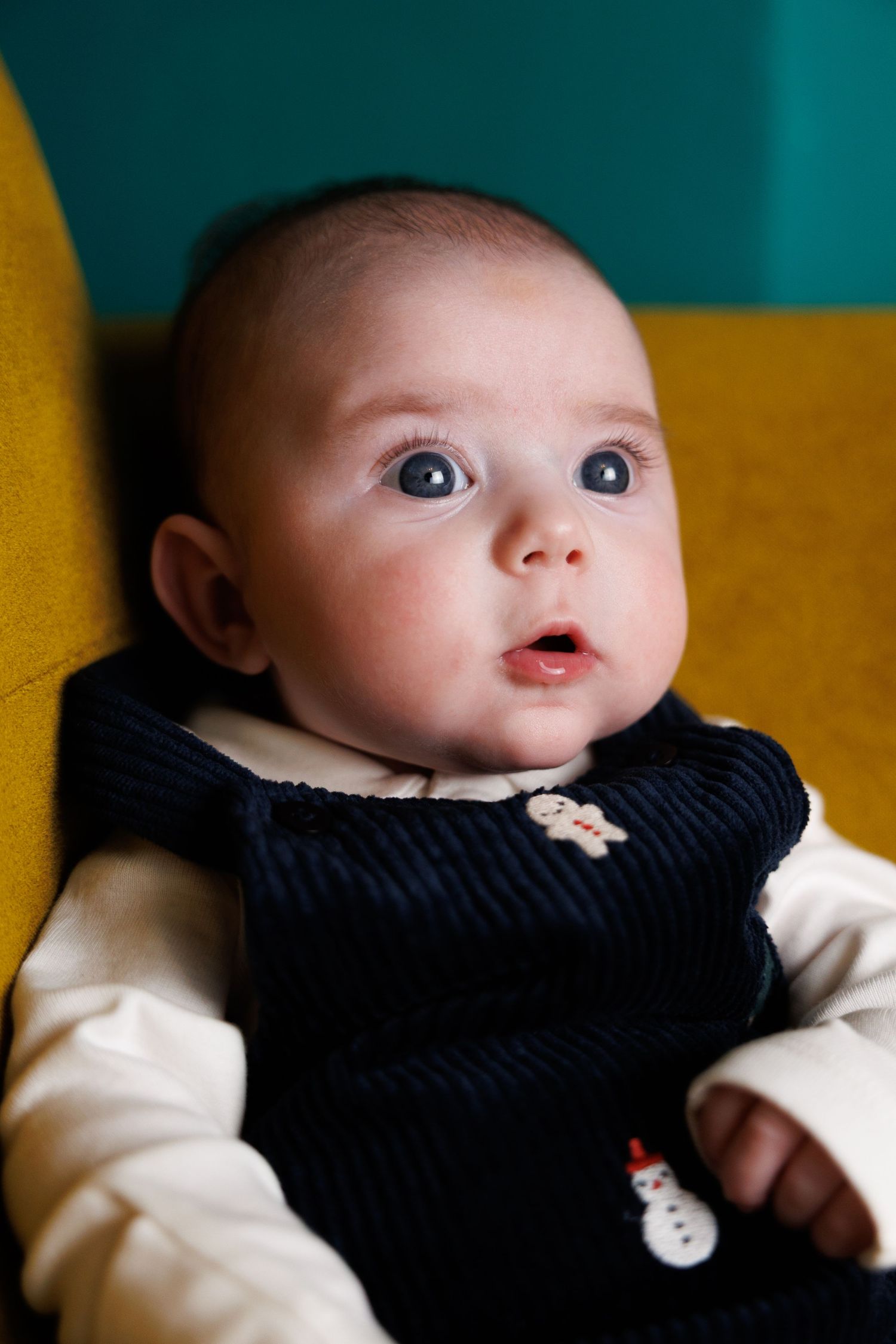 A series of four close-up shots showing a baby's expressive face against a turquoise and yellow background.