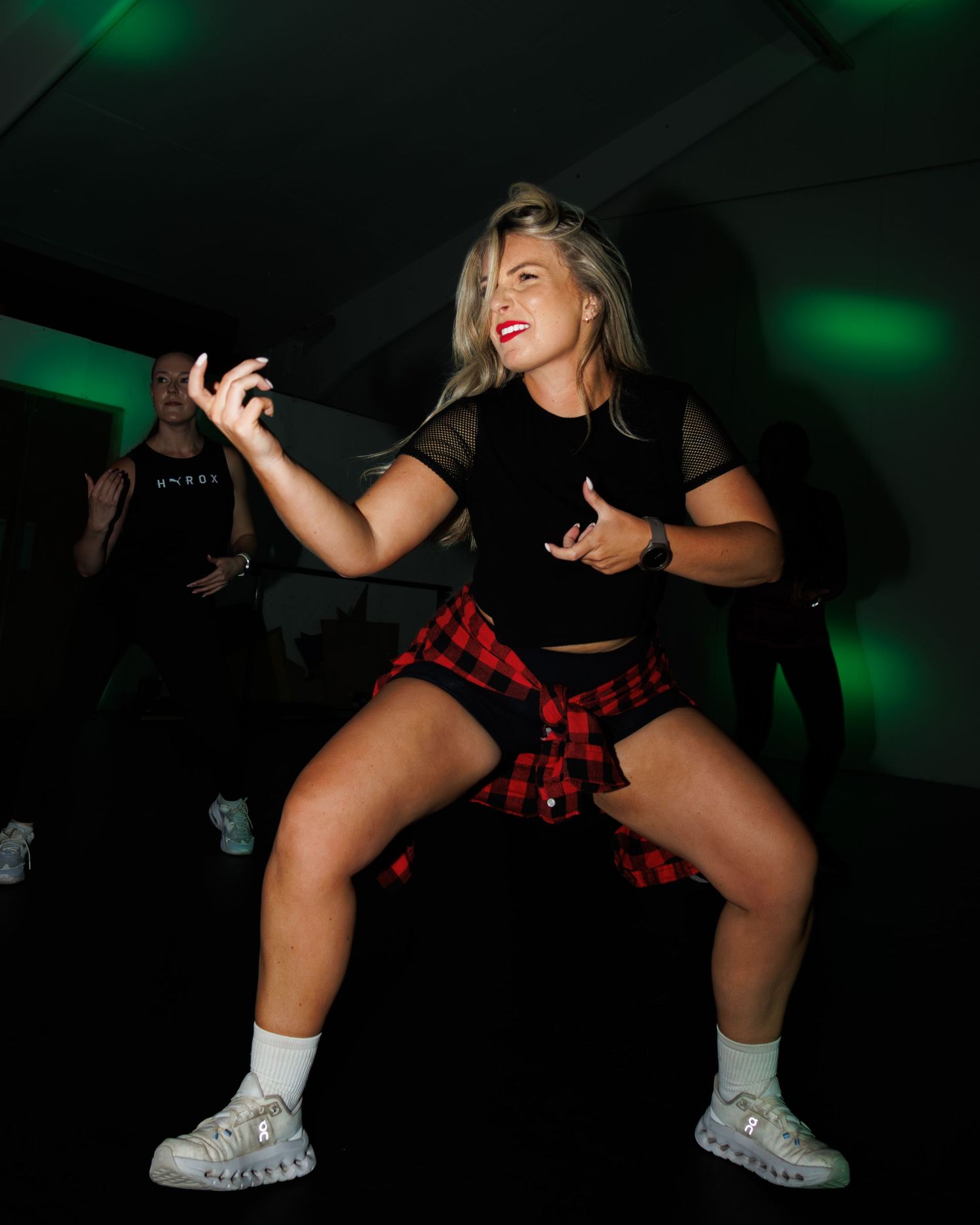 A dancer in black and red performs a dynamic dance move sequence against a dark background with green lighting effects.