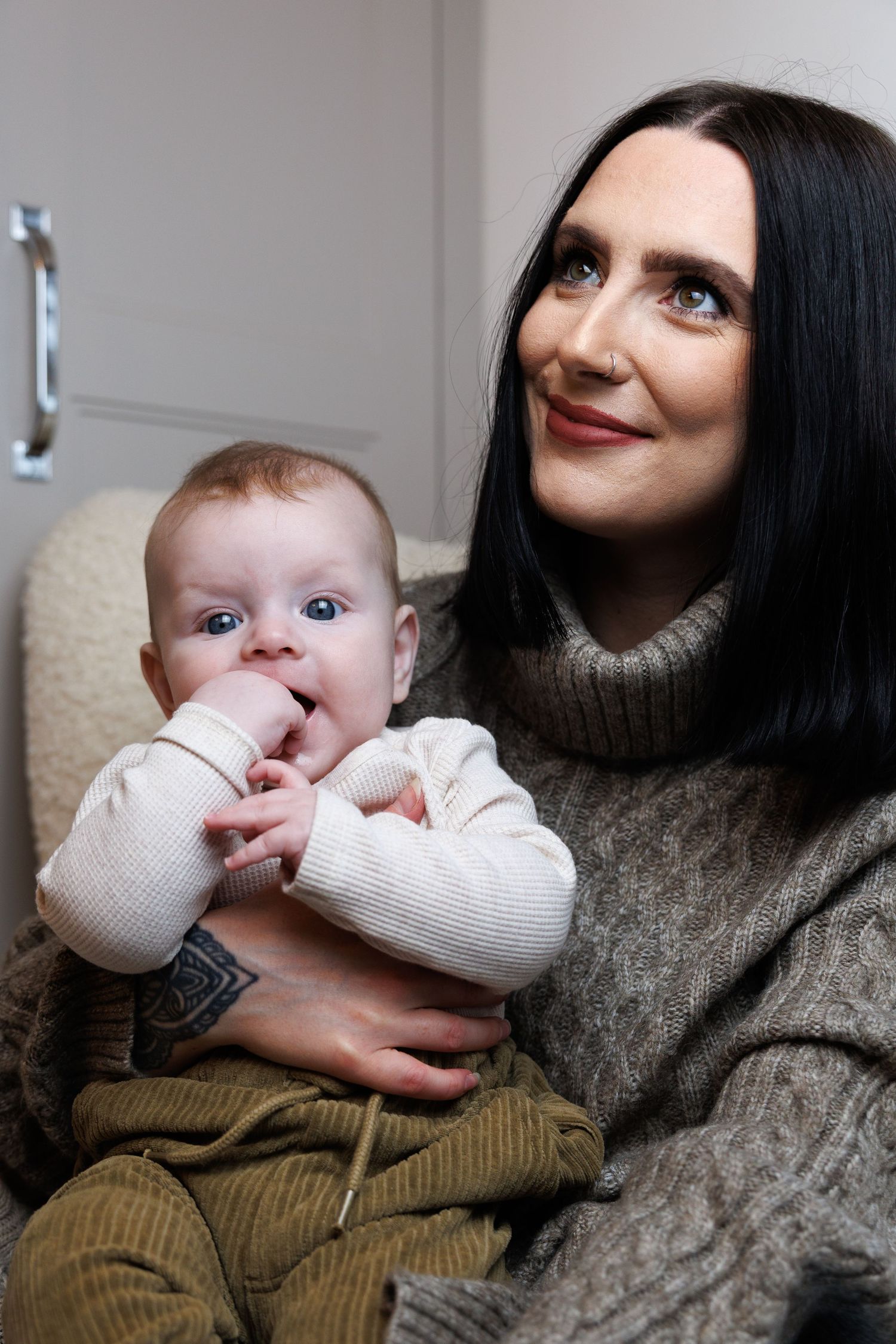 A baby in a white sweater is held lovingly while being bottle fed in a series of tender moments.